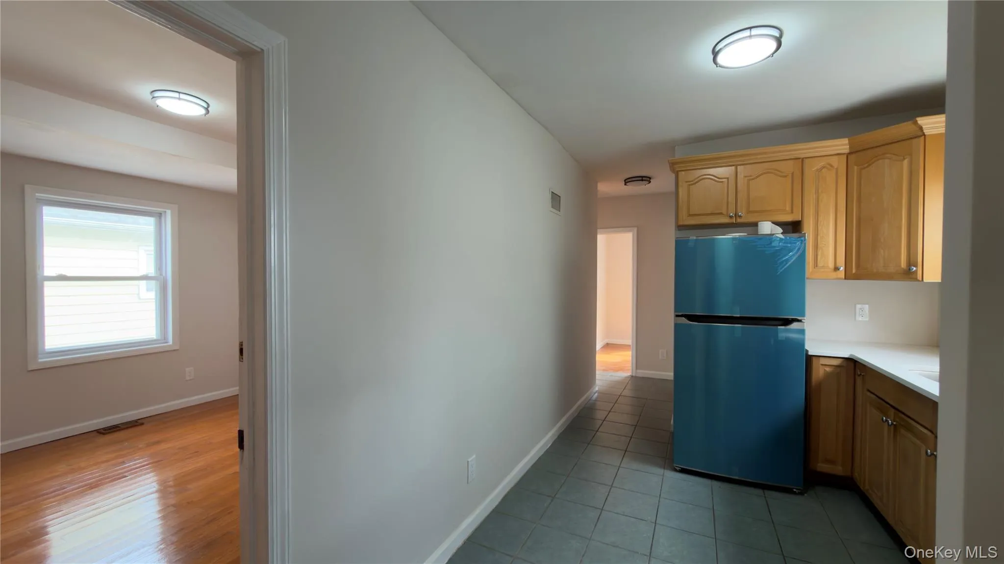 Kitchen with freestanding refrigerator, light countertops, and dark tile patterned floors Kitchen with freestanding refrigerator, light countertops, and dark tile patterned floors