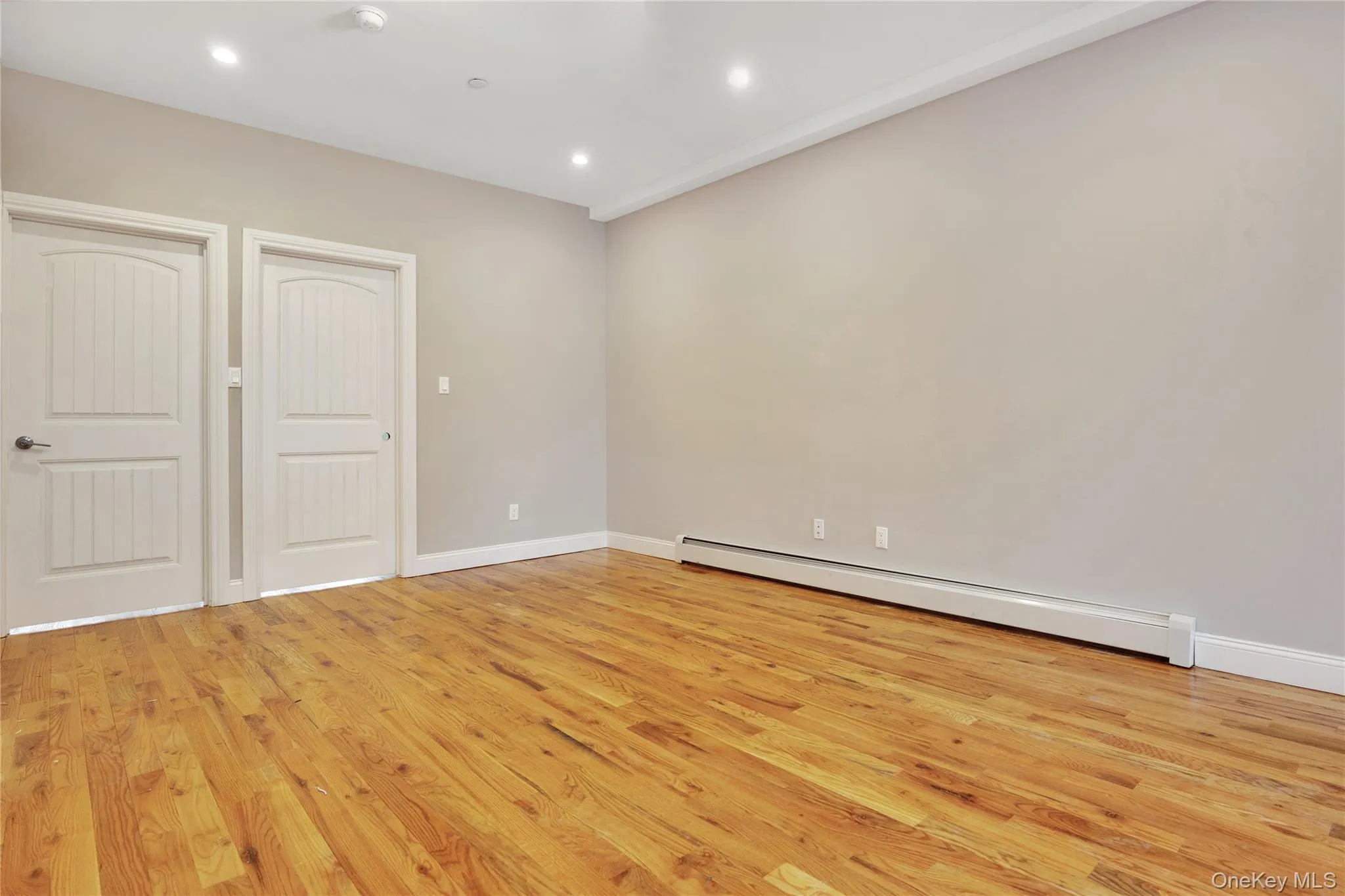 Empty room featuring baseboard heating, light wood finished floors, and recessed lighting Empty room featuring baseboard heating, light wood finished floors, and recessed lighting