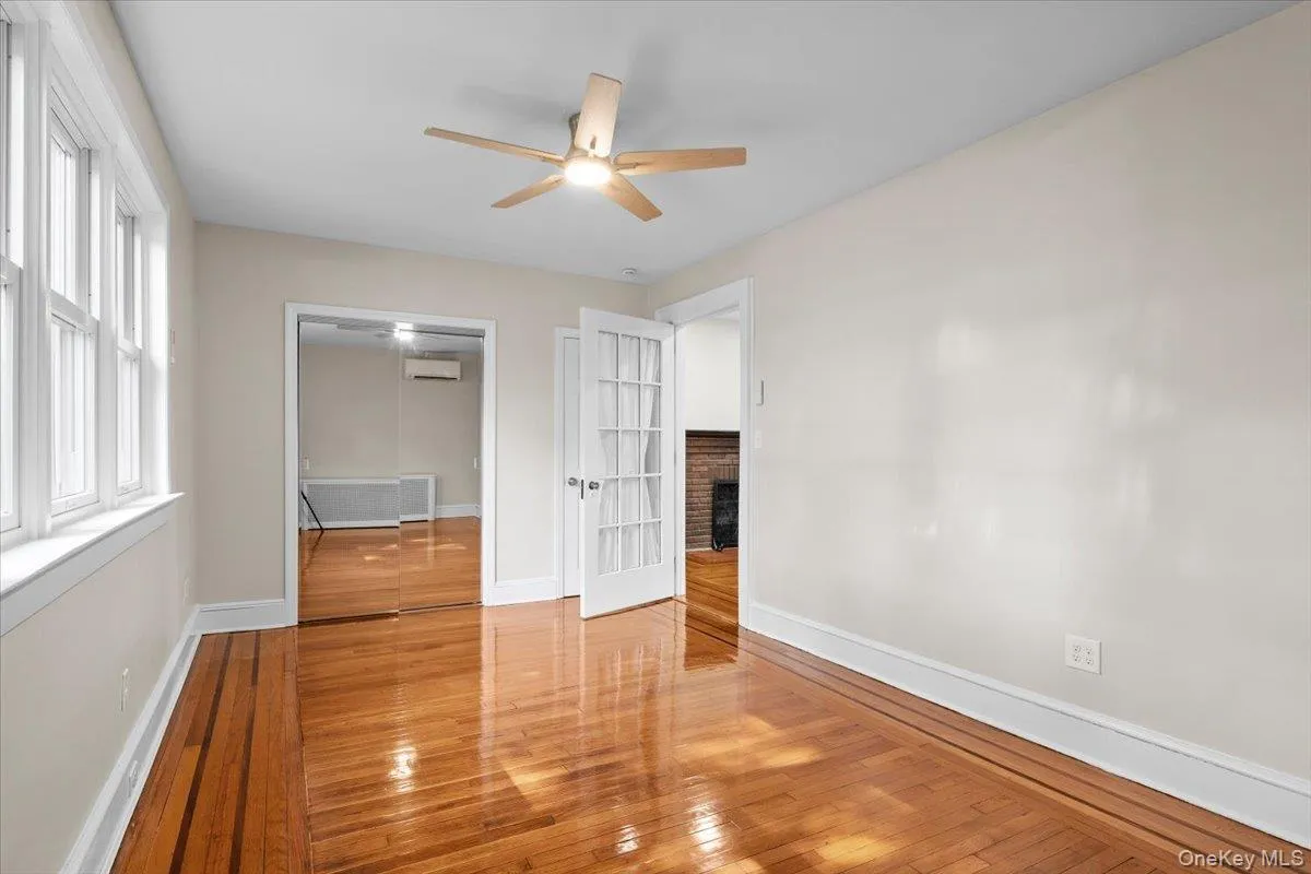 Unfurnished bedroom featuring wood-type flooring, a ceiling fan, and a wall mounted AC Unfurnished bedroom featuring wood-type flooring, a ceiling fan, and a wall mounted AC