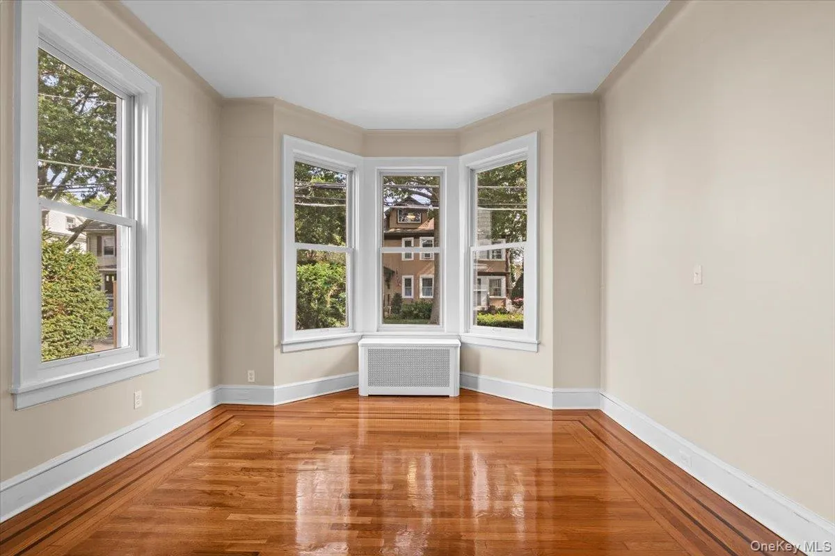 Unfurnished room with radiator and wood finished floors Unfurnished room with radiator and wood finished floors