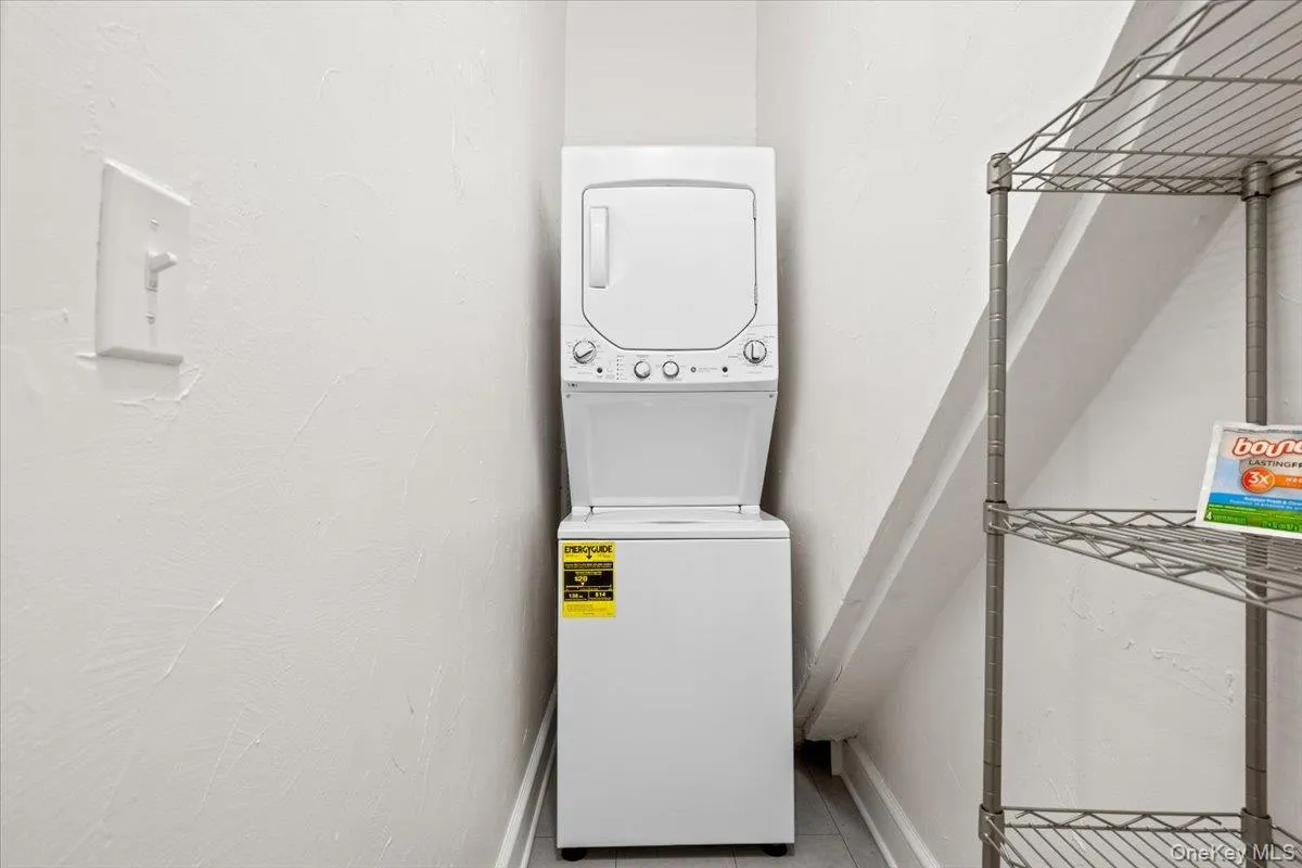 Laundry area with stacked washing machine and dryer and tile patterned floors Laundry area with stacked washing machine and dryer and tile patterned floors