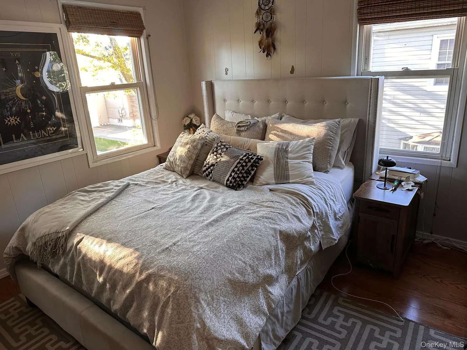 Bedroom featuring wood walls, wood finished floors, and multiple windows Bedroom featuring wood walls, wood finished floors, and multiple windows