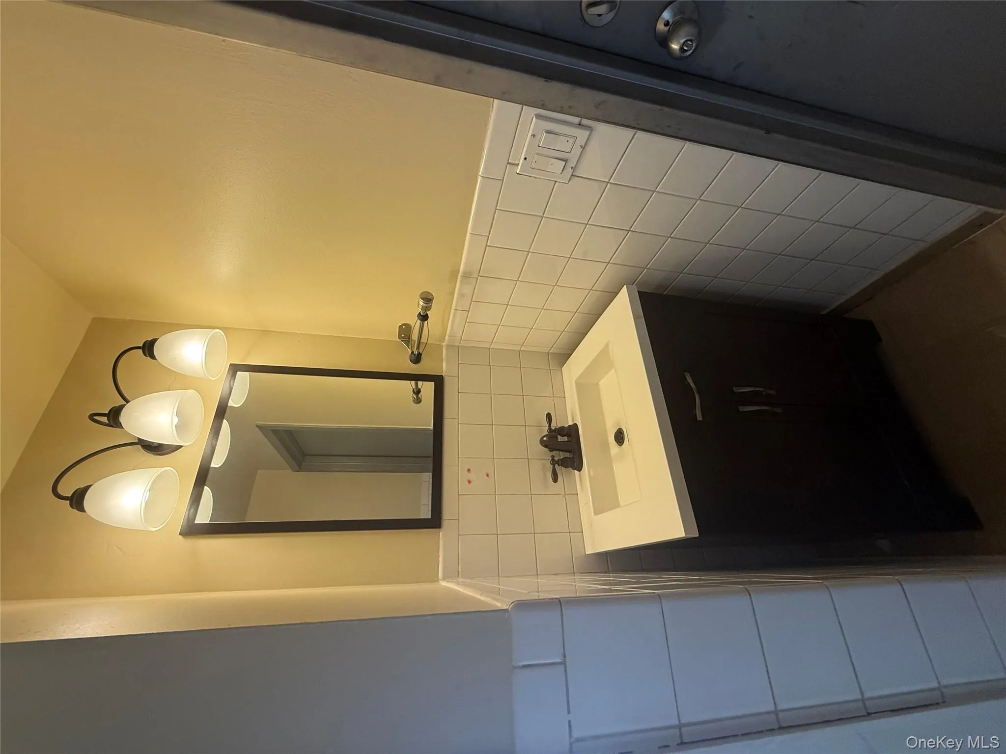 Half bathroom featuring tile walls, vanity, wainscoting, and dark tile patterned floors Half bathroom featuring tile walls, vanity, wainscoting, and dark tile patterned floors