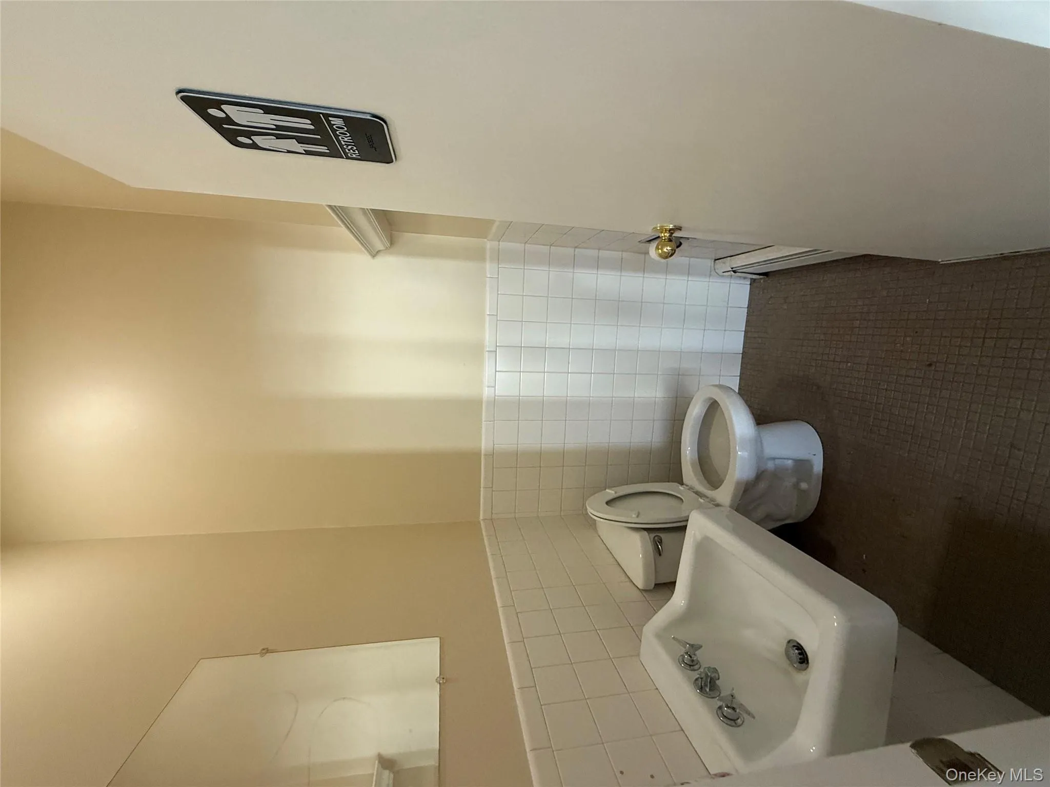 Half bathroom with tile walls, a wainscoted wall, dark tile patterned floors, and a baseboard radiator Half bathroom with tile walls, a wainscoted wall, dark tile patterned floors, and a baseboard radiator