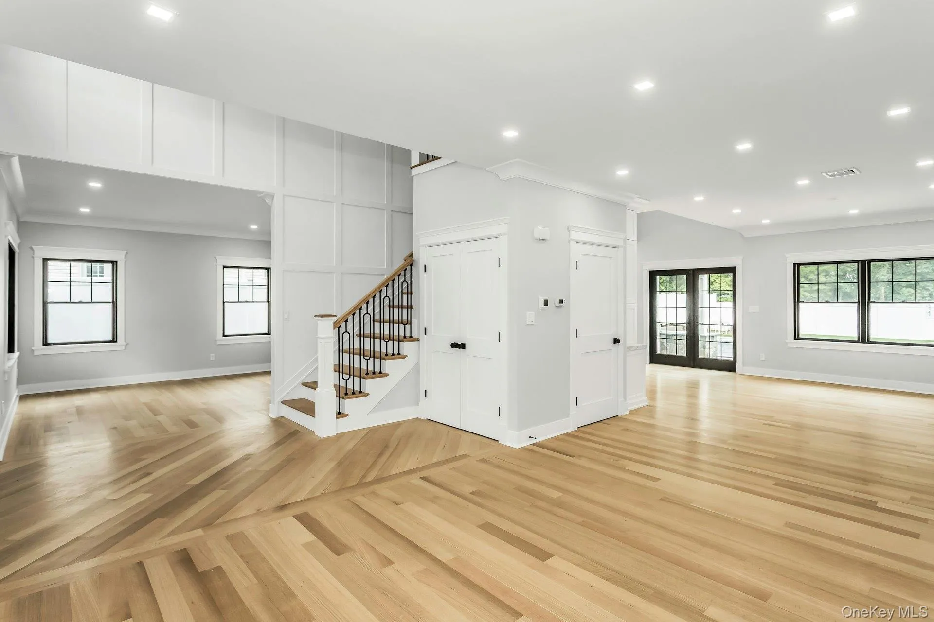 Unfurnished living room featuring stairway, healthy amount of natural light, recessed lighting, crown molding, and parquet floors Unfurnished living room featuring stairway, healthy amount of natural light, recessed lighting, crown molding, and parquet floors