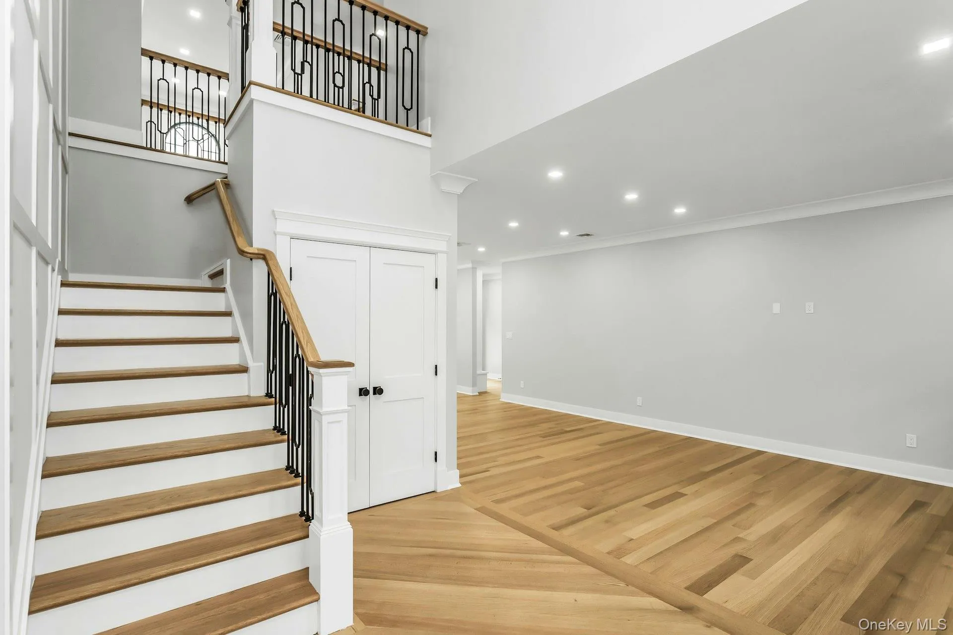 Stairway with recessed lighting, wood finished floors, a high ceiling, and ornamental molding Stairway with recessed lighting, wood finished floors, a high ceiling, and ornamental molding