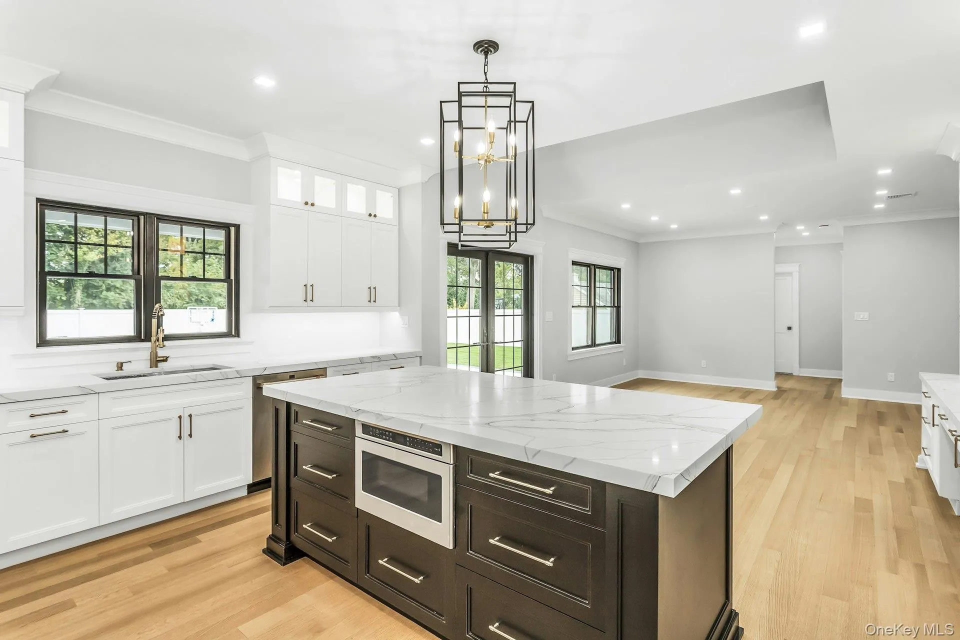 Kitchen featuring white cabinetry, ornamental molding, light stone countertops, light wood finished floors, and recessed lighting Kitchen featuring white cabinetry, ornamental molding, light stone countertops, light wood finished floors, and recessed lighting