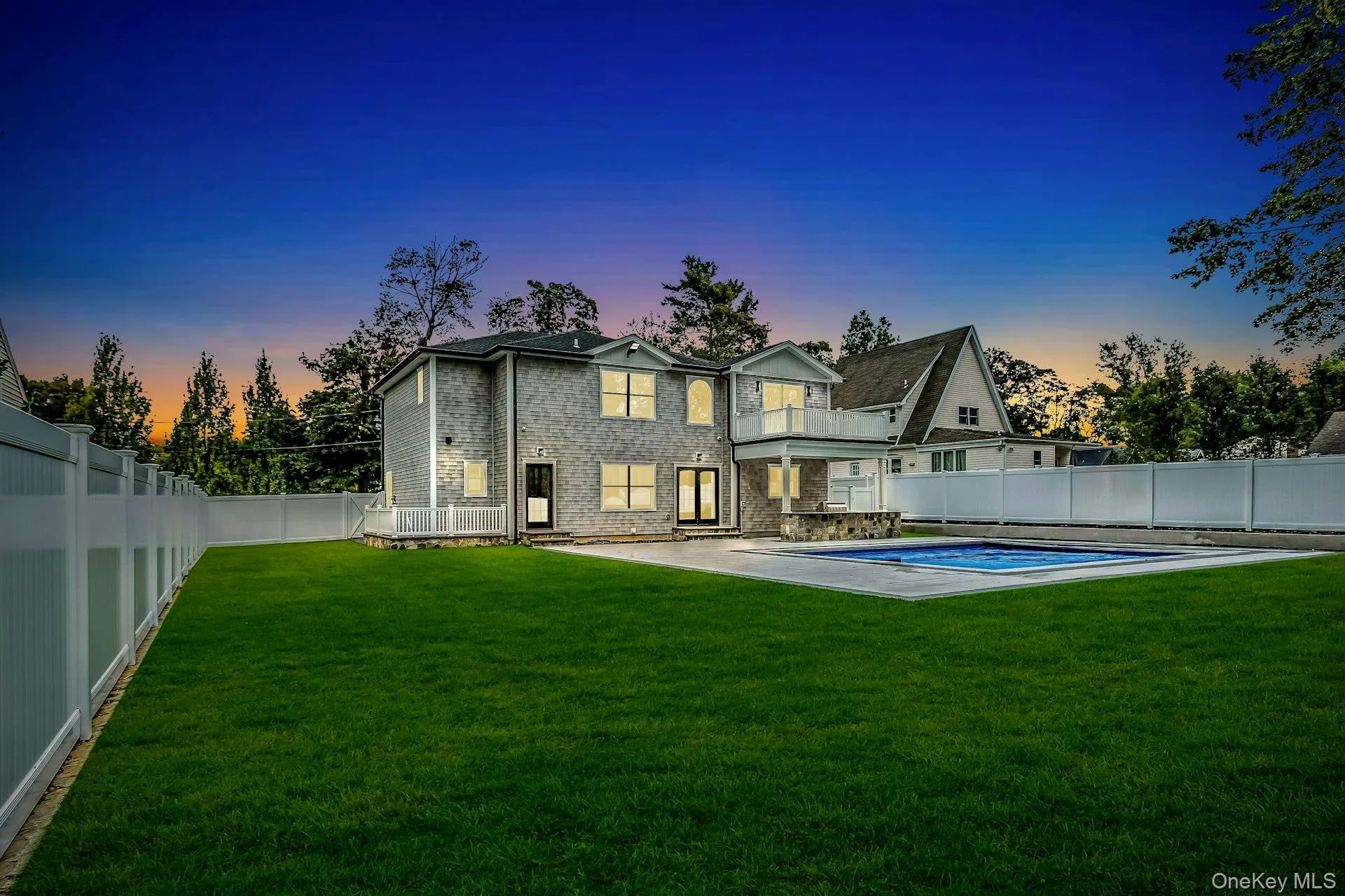 Back of house at dusk featuring a fenced backyard, a patio, and a balcony Back of house at dusk featuring a fenced backyard, a patio, and a balcony