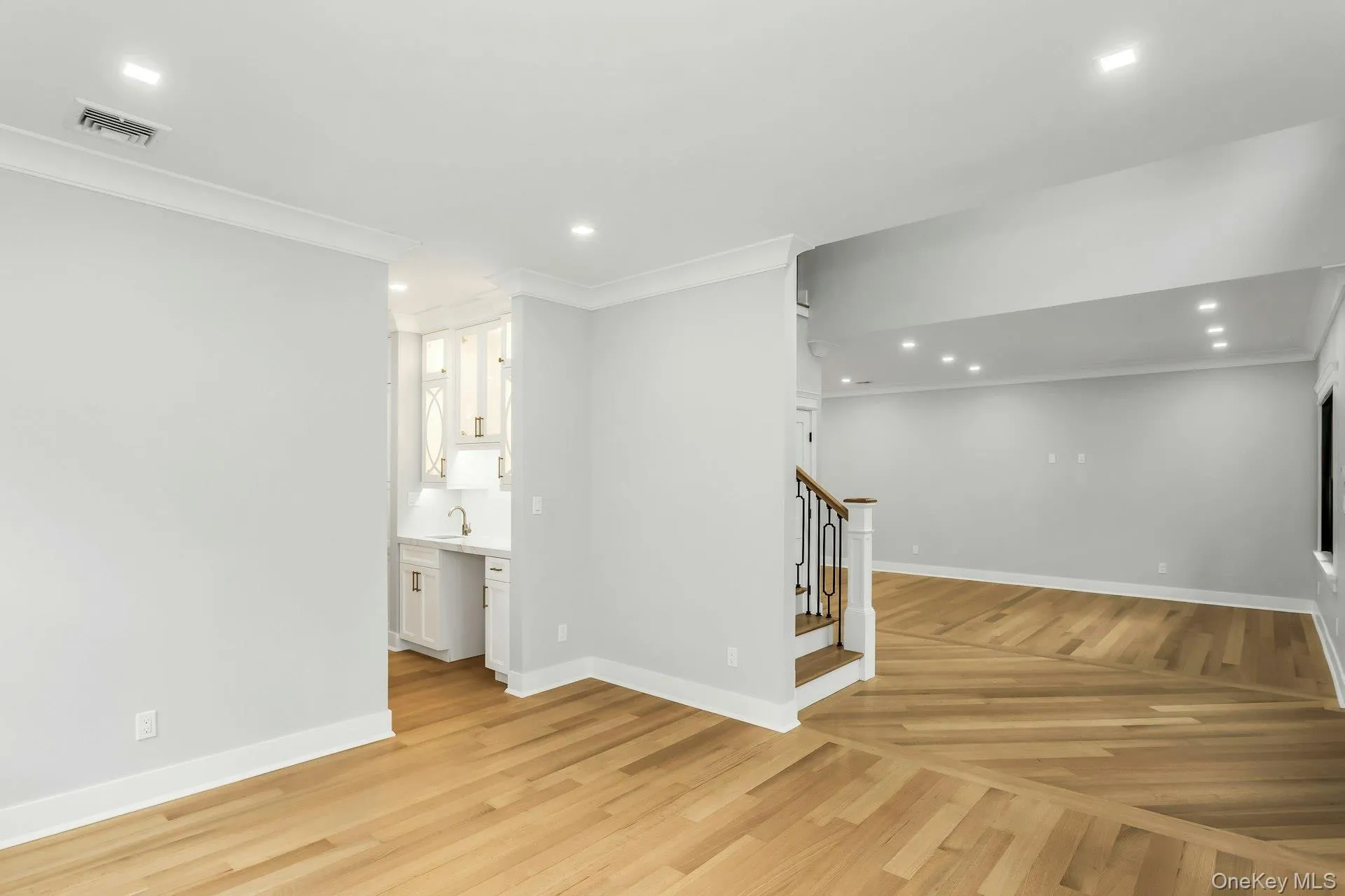 Below grade area featuring crown molding, recessed lighting, light wood-style flooring, and stairs Below grade area featuring crown molding, recessed lighting, light wood-style flooring, and stairs