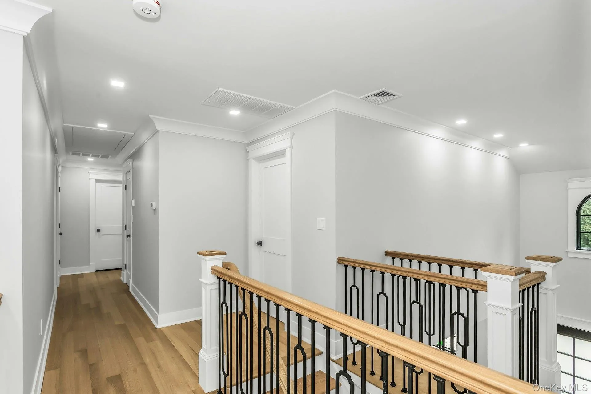 Hallway featuring recessed lighting, an upstairs landing, attic access, light wood-type flooring, and ornamental molding Hallway featuring recessed lighting, an upstairs landing, attic access, light wood-type flooring, and ornamental molding