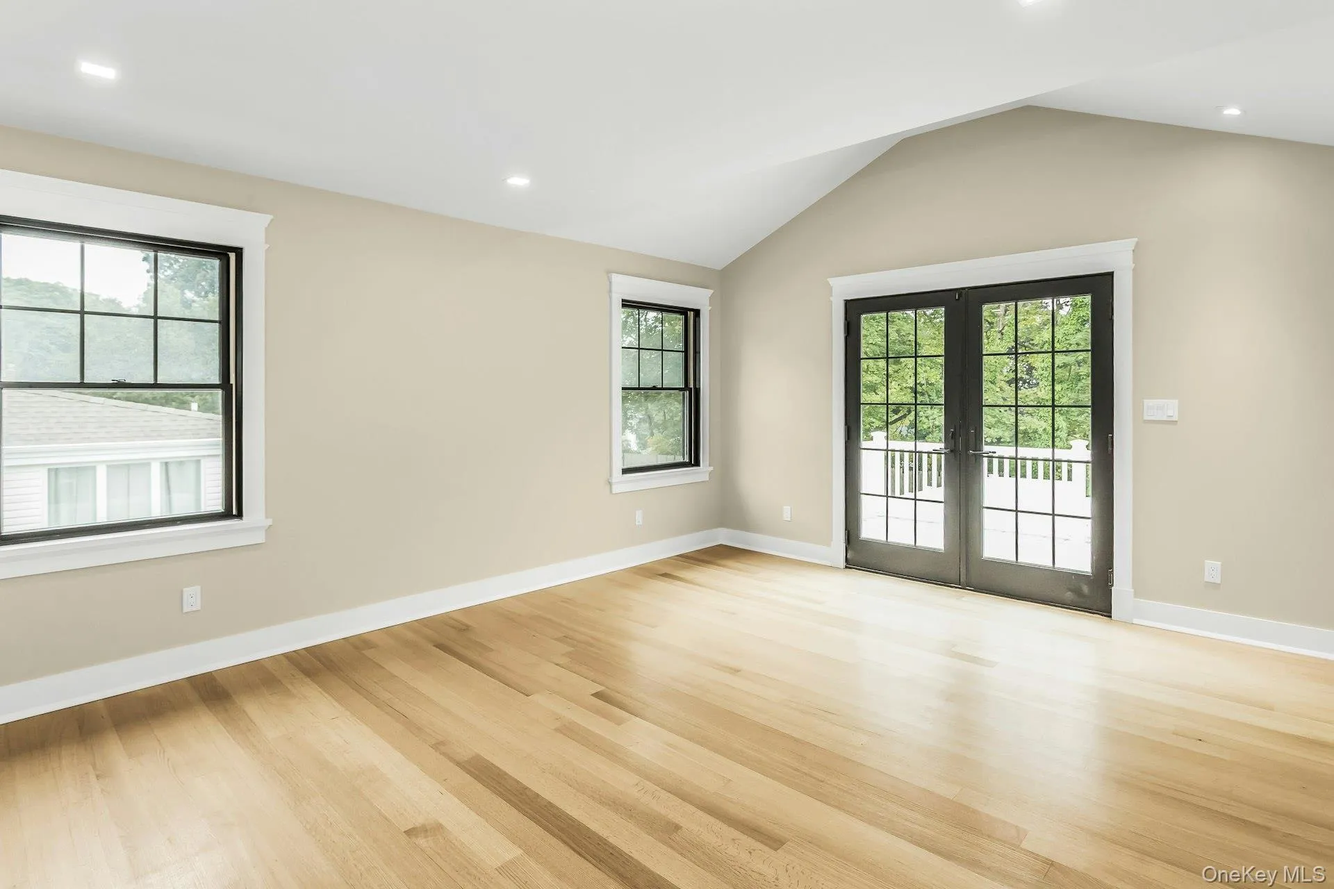 Unfurnished room with recessed lighting, light wood finished floors, lofted ceiling, and french doors Unfurnished room with recessed lighting, light wood finished floors, lofted ceiling, and french doors