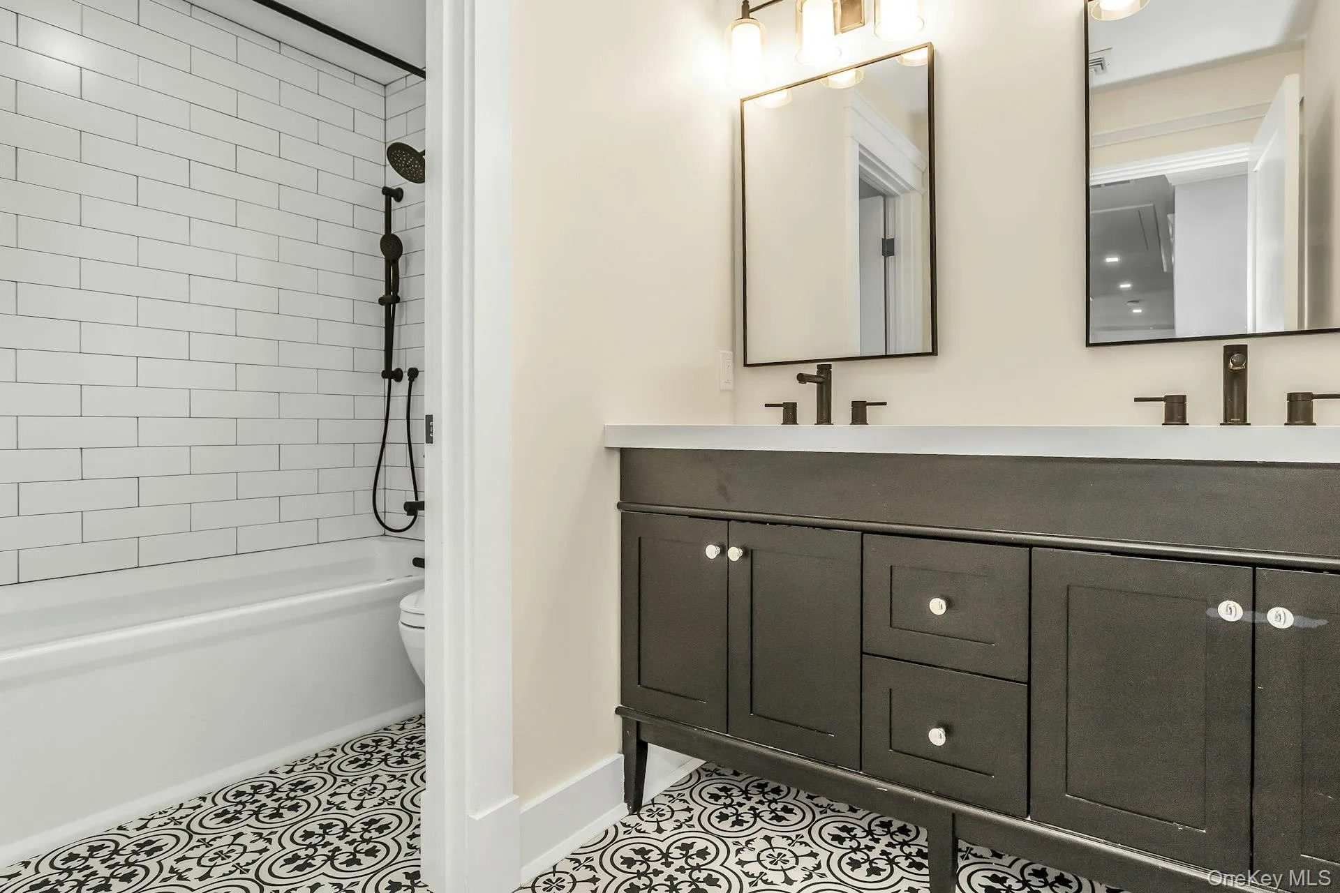 Full bath featuring double vanity, shower / bath combination, and light tile patterned flooring Full bath featuring double vanity, shower / bath combination, and light tile patterned flooring