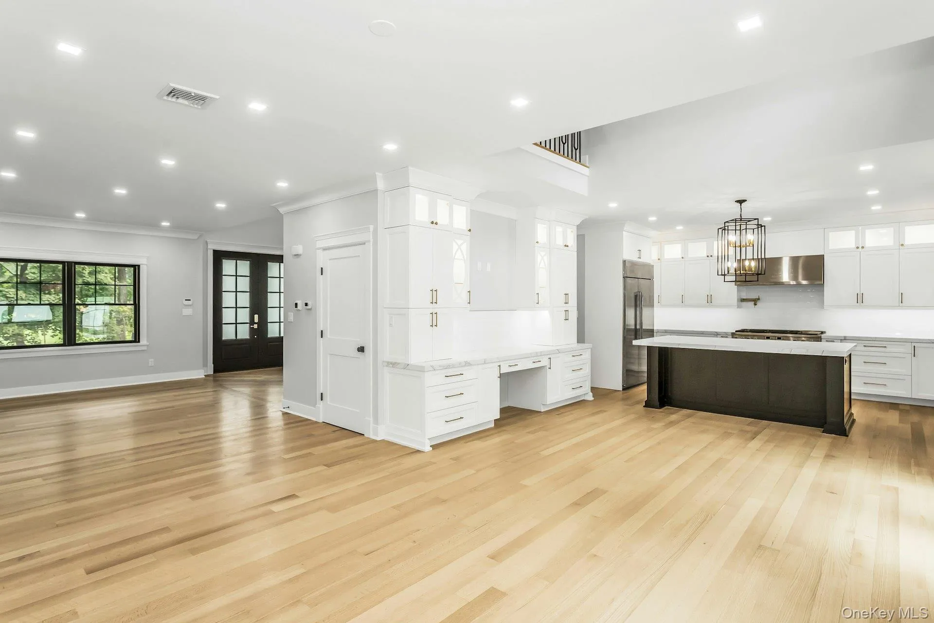 Kitchen with glass insert cabinets, open floor plan, white cabinetry, recessed lighting, and stainless steel built in refrigerator Kitchen with glass insert cabinets, open floor plan, white cabinetry, recessed lighting, and stainless steel built in refrigerator