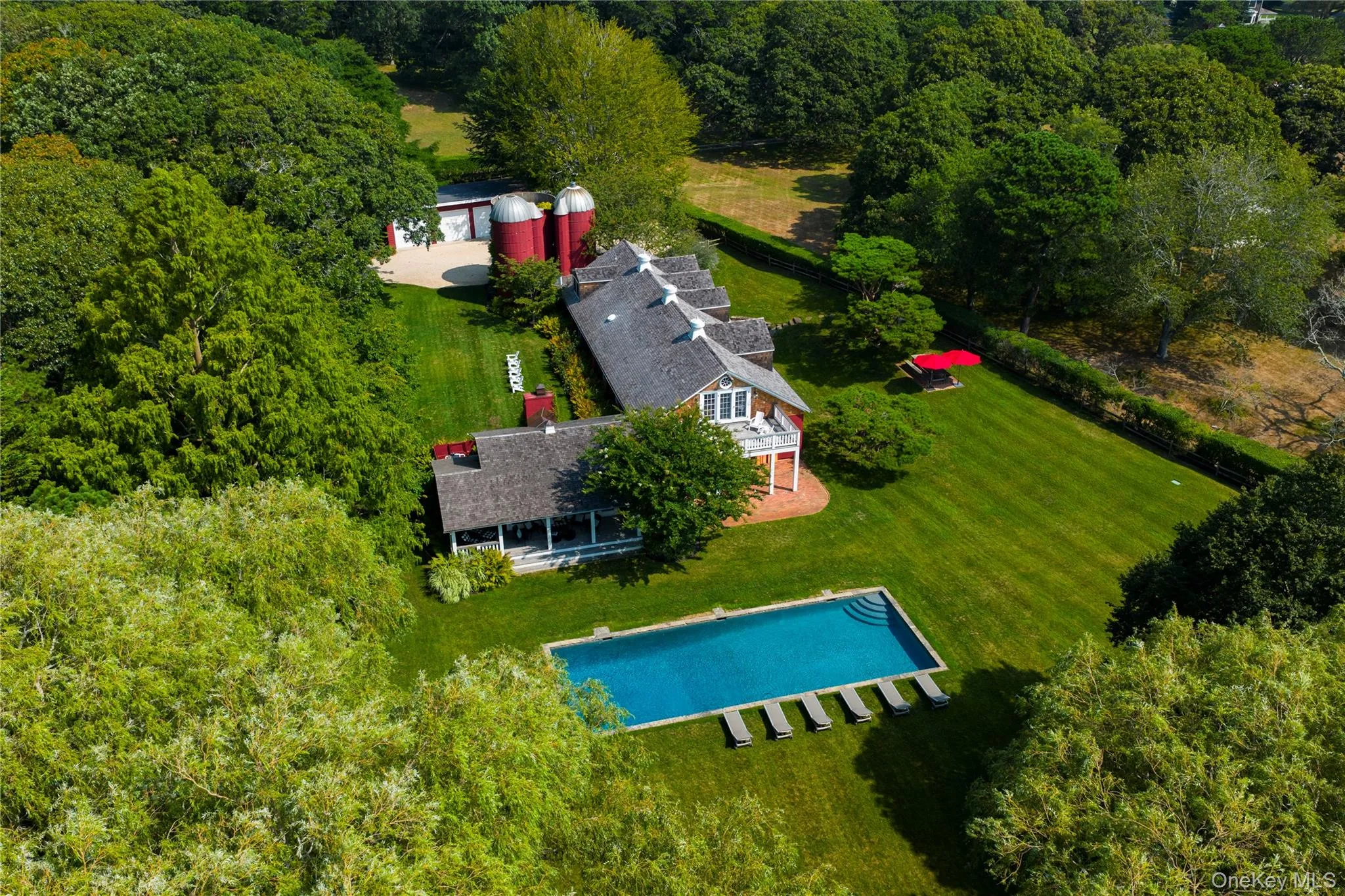 Aerial view of property and surrounding area featuring a pool and a heavily wooded area Aerial view of property and surrounding area featuring a pool and a heavily wooded area
