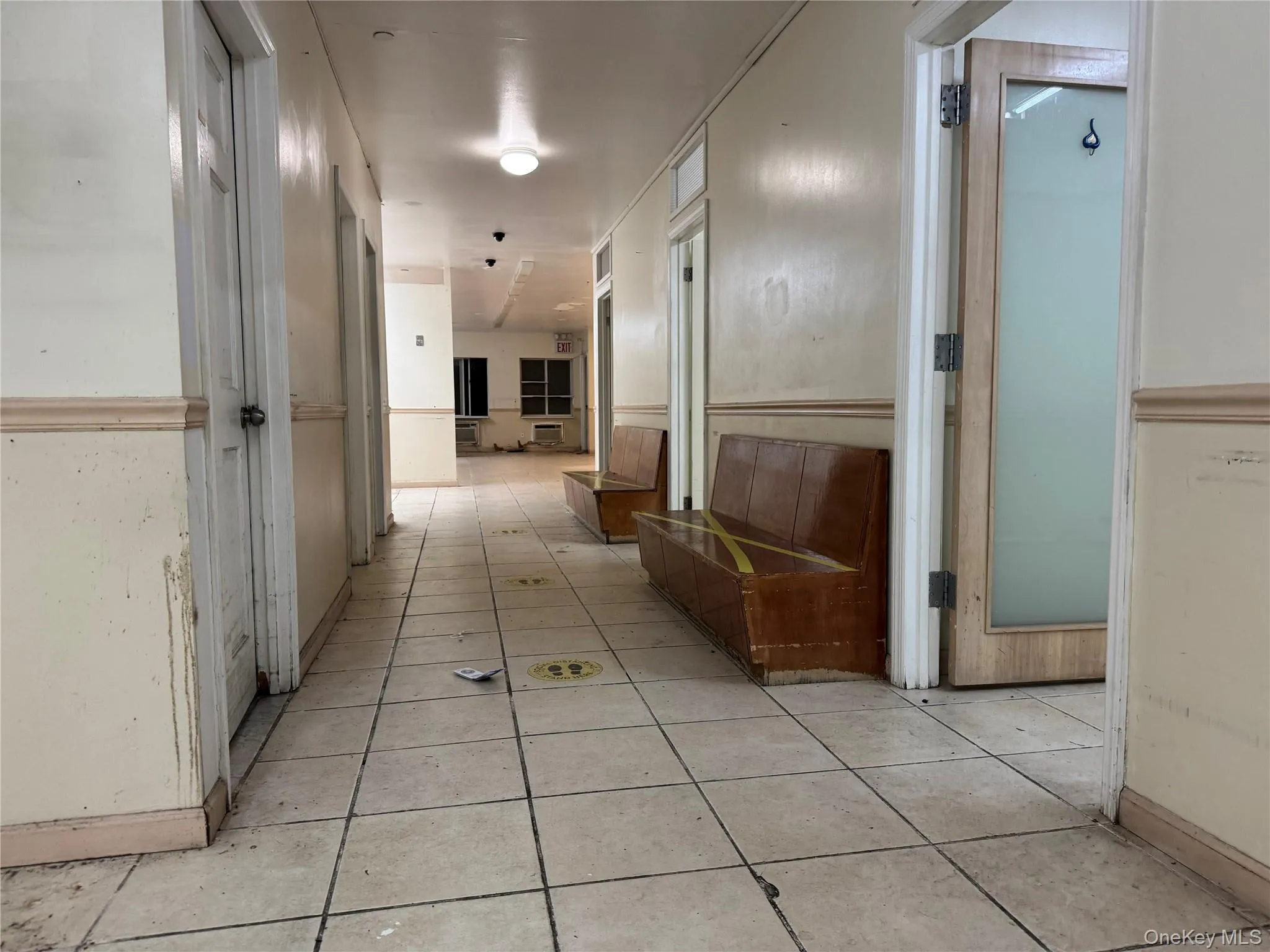 Corridor featuring light tile patterned flooring and baseboards Corridor featuring light tile patterned flooring and baseboards