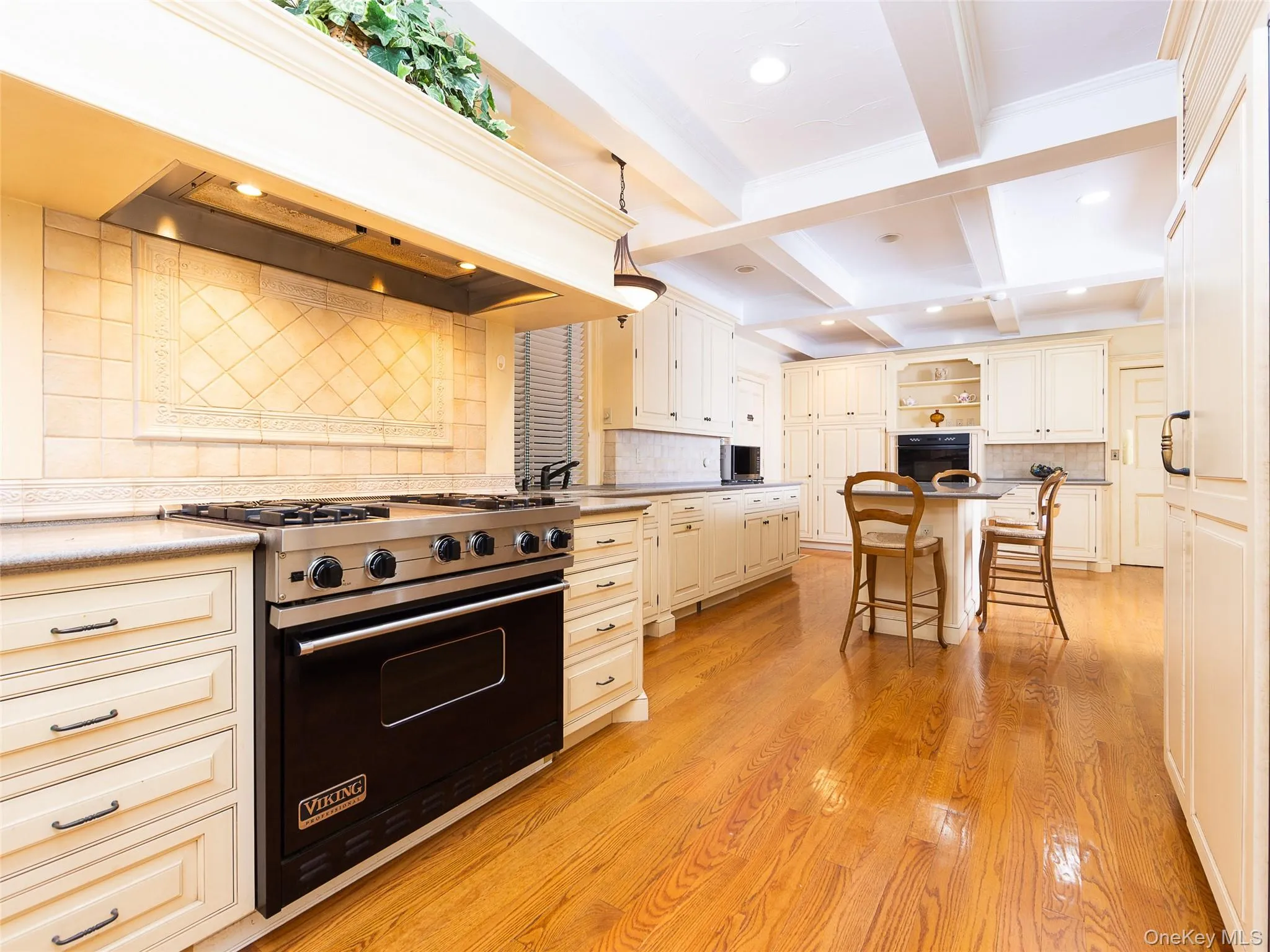 Kitchen featuring tasteful backsplash, a breakfast bar area, open shelves, black appliances, and premium range hood Kitchen featuring tasteful backsplash, a breakfast bar area, open shelves, black appliances, and premium range hood