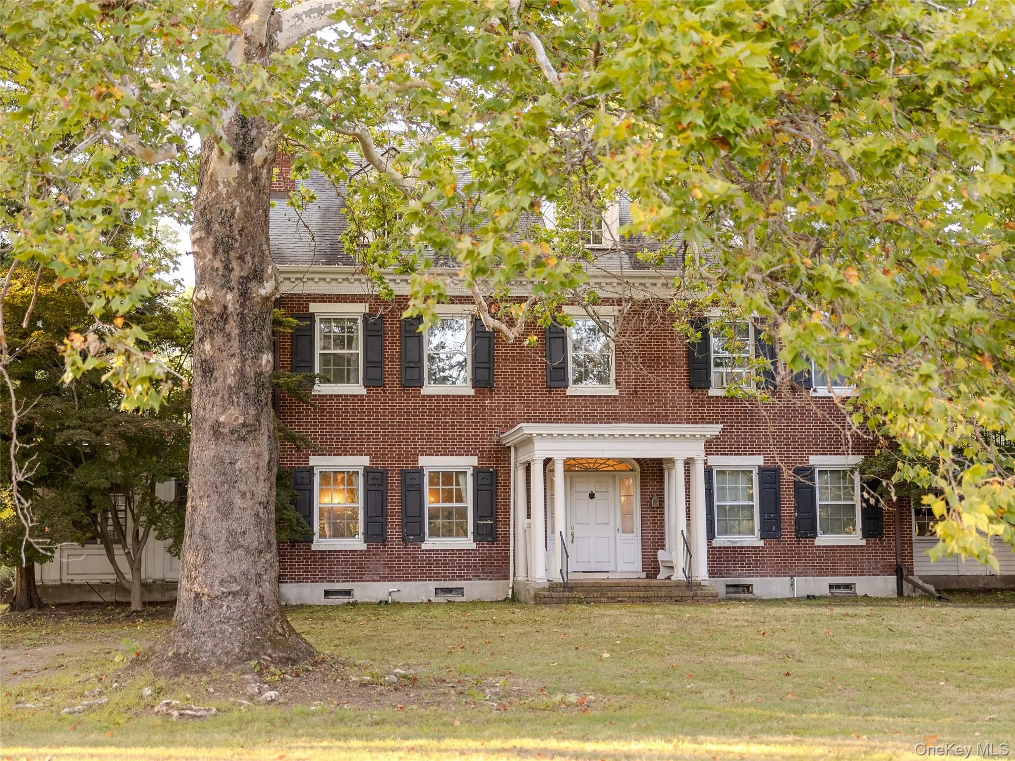Georgian-style home featuring brick siding, a front lawn, and crawl space Georgian-style home featuring brick siding, a front lawn, and crawl space