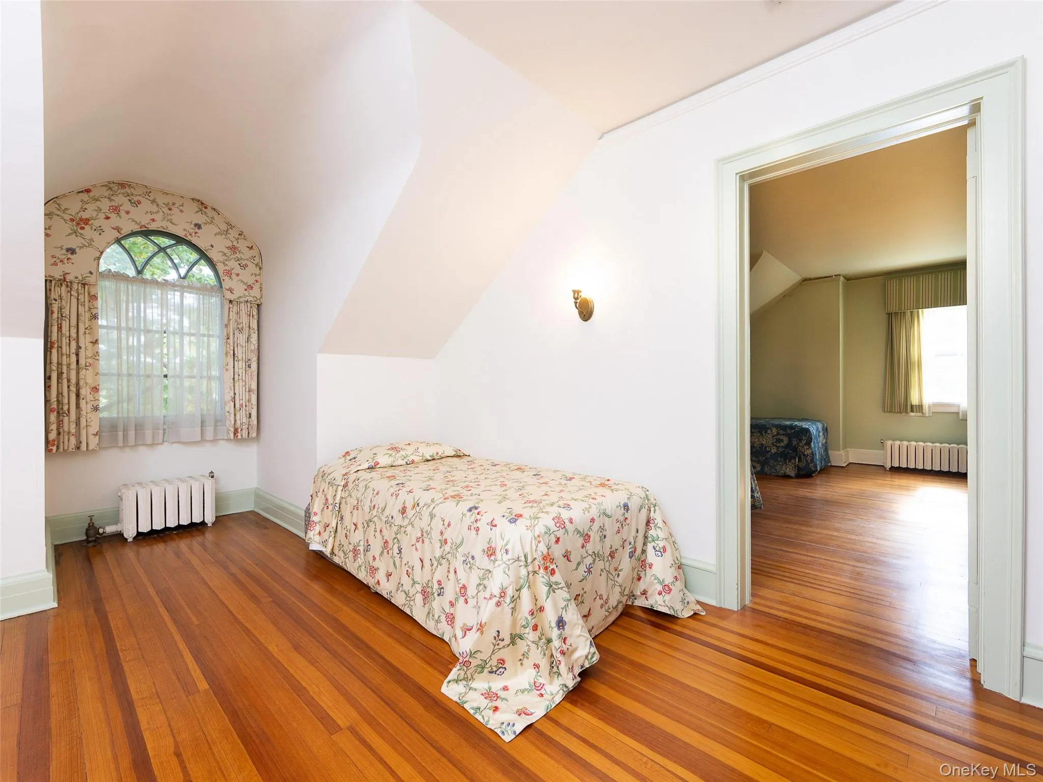 Bedroom featuring lofted ceiling, wood-type flooring, and radiator Bedroom featuring lofted ceiling, wood-type flooring, and radiator