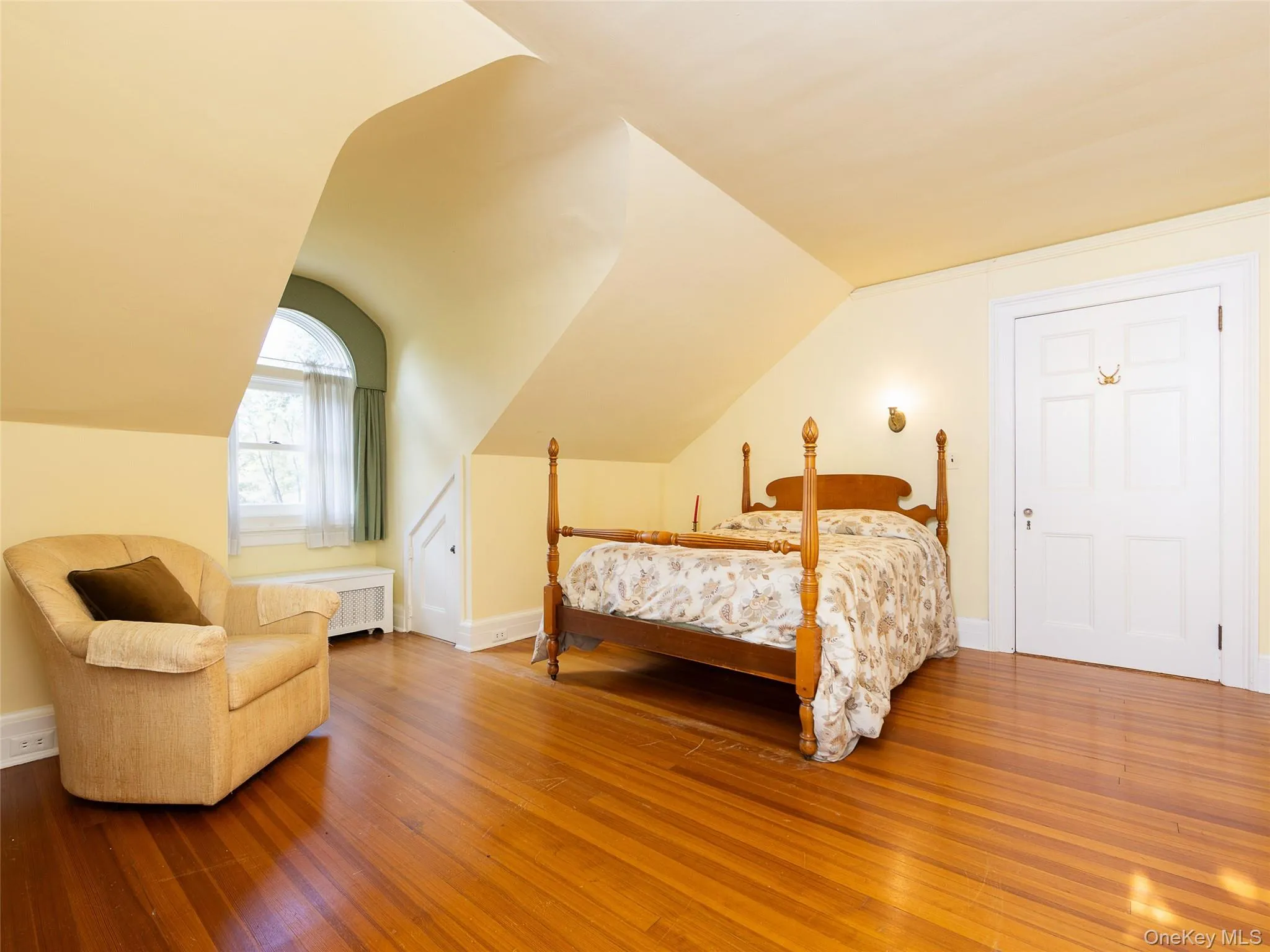 Bedroom with hardwood / wood-style flooring, radiator heating unit, and vaulted ceiling Bedroom with hardwood / wood-style flooring, radiator heating unit, and vaulted ceiling
