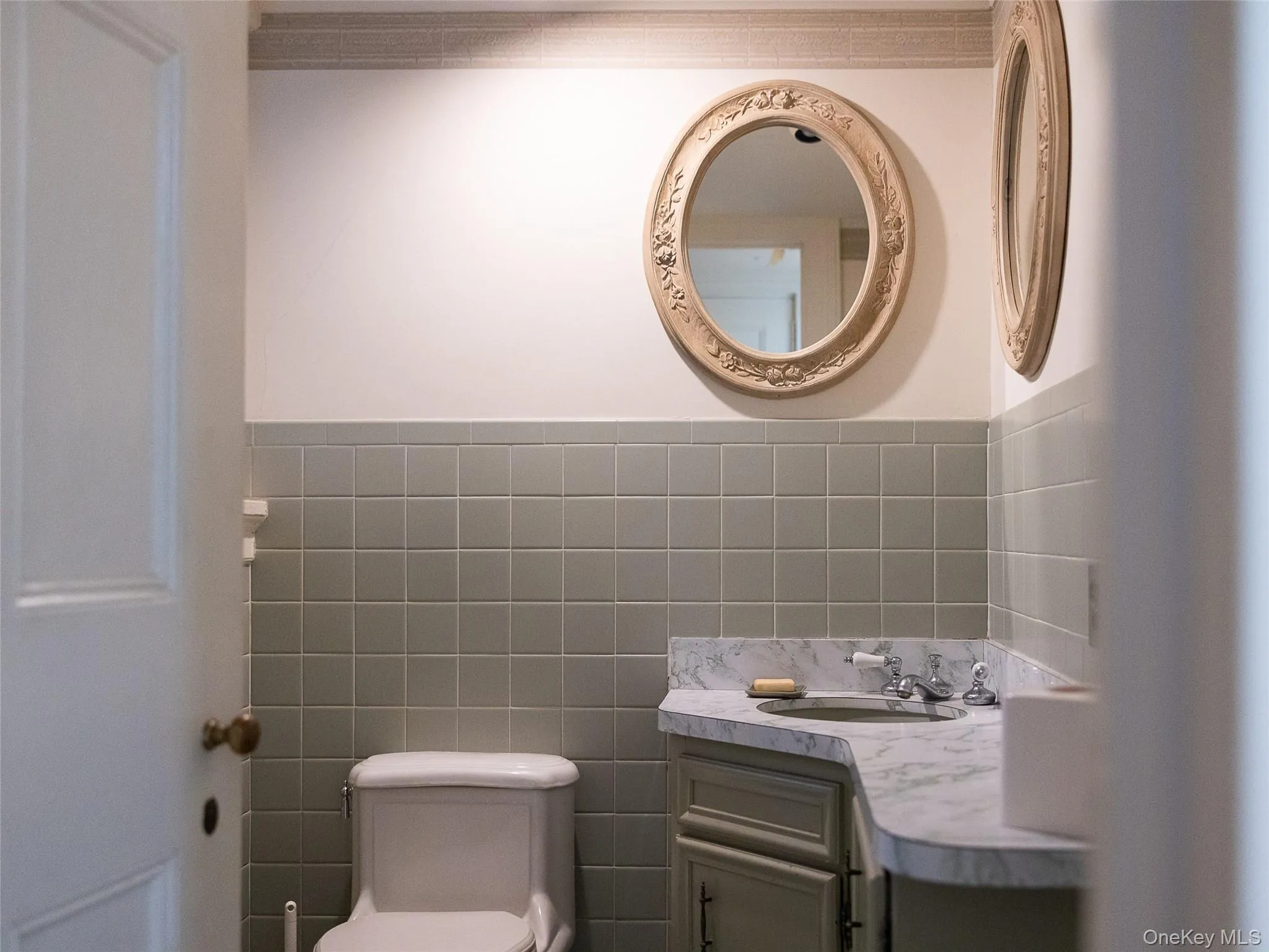 Bathroom with tile walls, vanity, and wainscoting Bathroom with tile walls, vanity, and wainscoting
