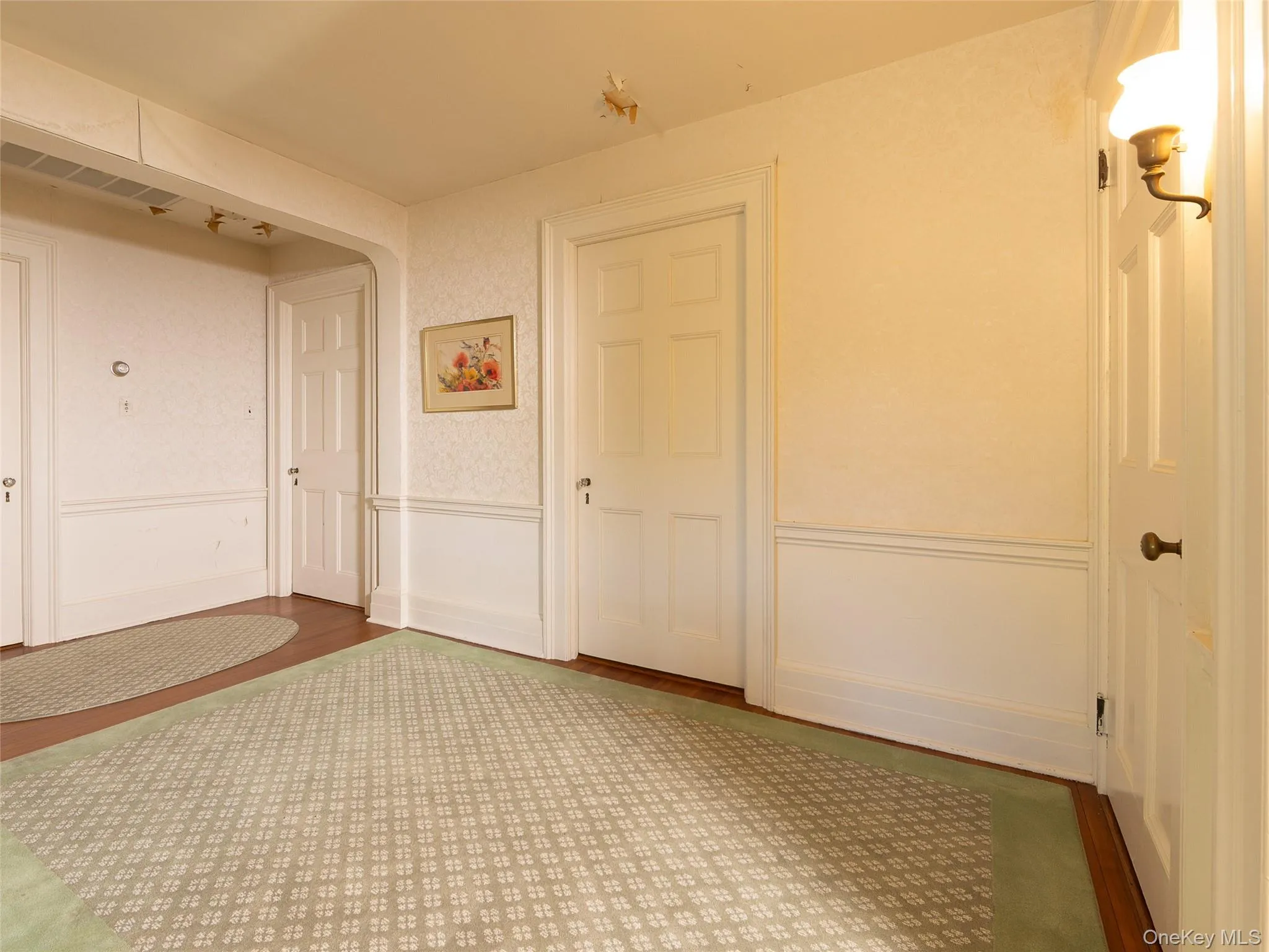 Hall featuring wainscoting, wood finished floors, and arched walkways Hall featuring wainscoting, wood finished floors, and arched walkways