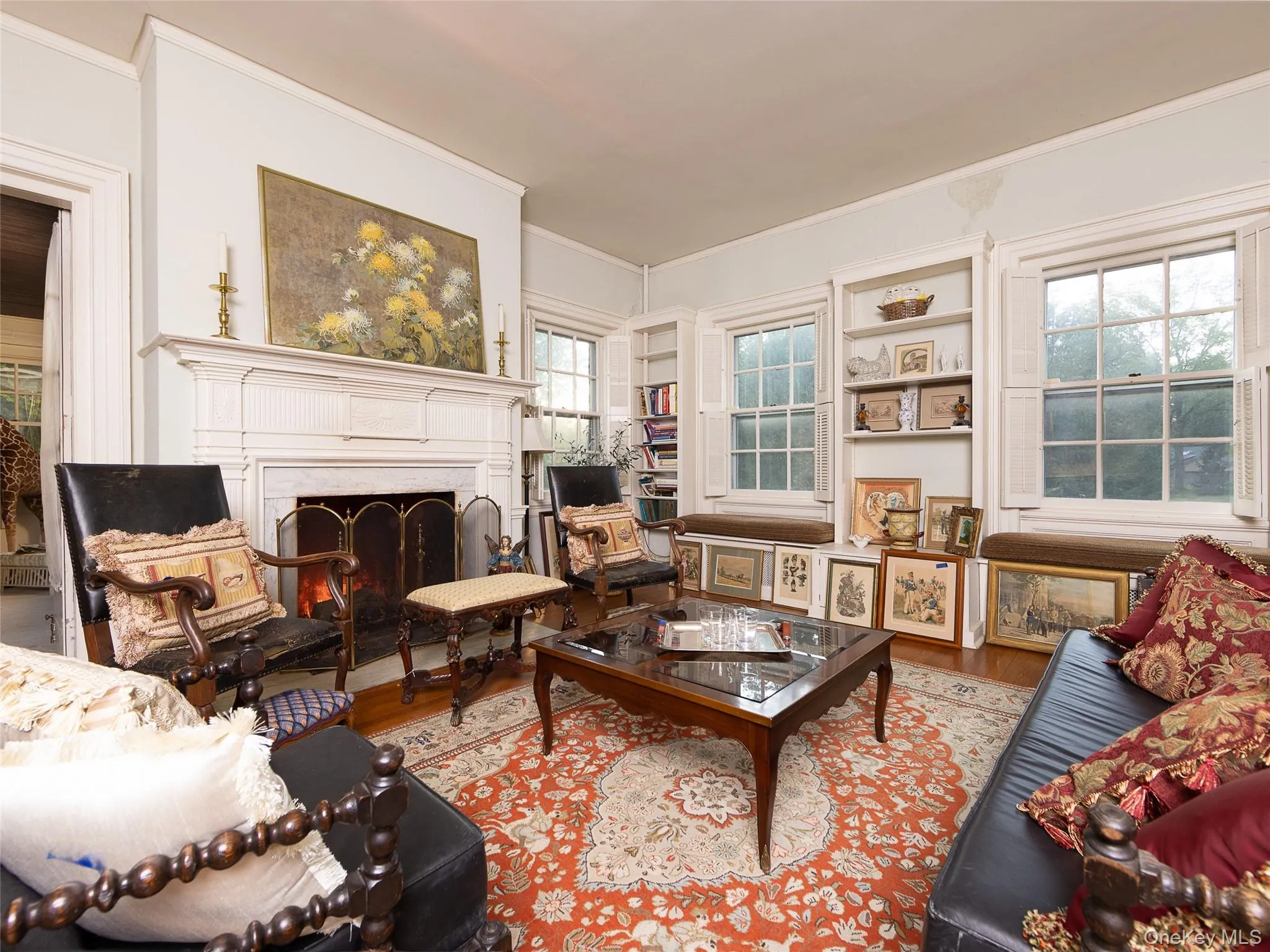 Living room featuring ornamental molding, a warm lit fireplace, and wood finished floors Living room featuring ornamental molding, a warm lit fireplace, and wood finished floors