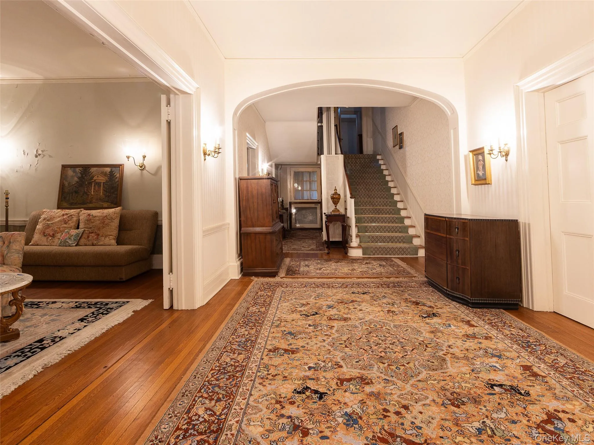 Hall featuring hardwood / wood-style flooring, stairs, arched walkways, and ornamental molding Hall featuring hardwood / wood-style flooring, stairs, arched walkways, and ornamental molding