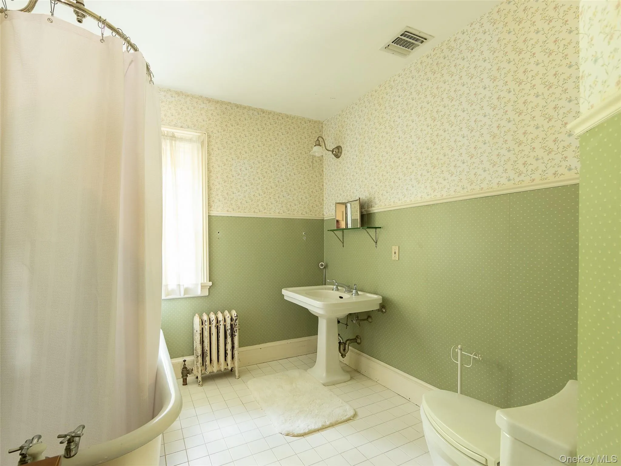 Full bath with radiator, light tile patterned flooring, wallpapered walls, and a wainscoted wall Full bath with radiator, light tile patterned flooring, wallpapered walls, and a wainscoted wall
