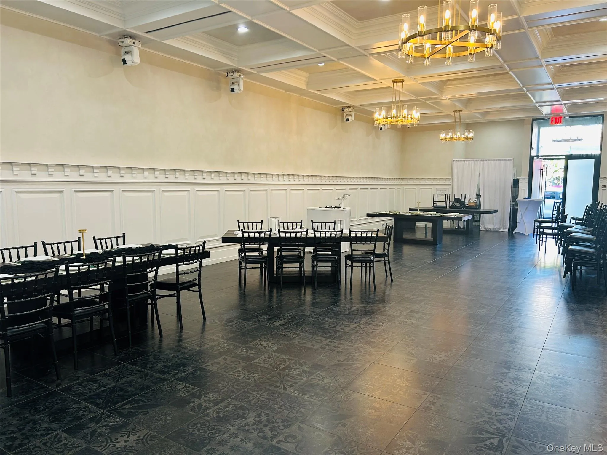 Dining space featuring coffered ceiling, a decorative wall, beam ceiling, a wainscoted wall, and a chandelier Dining space featuring coffered ceiling, a decorative wall, beam ceiling, a wainscoted wall, and a chandelier