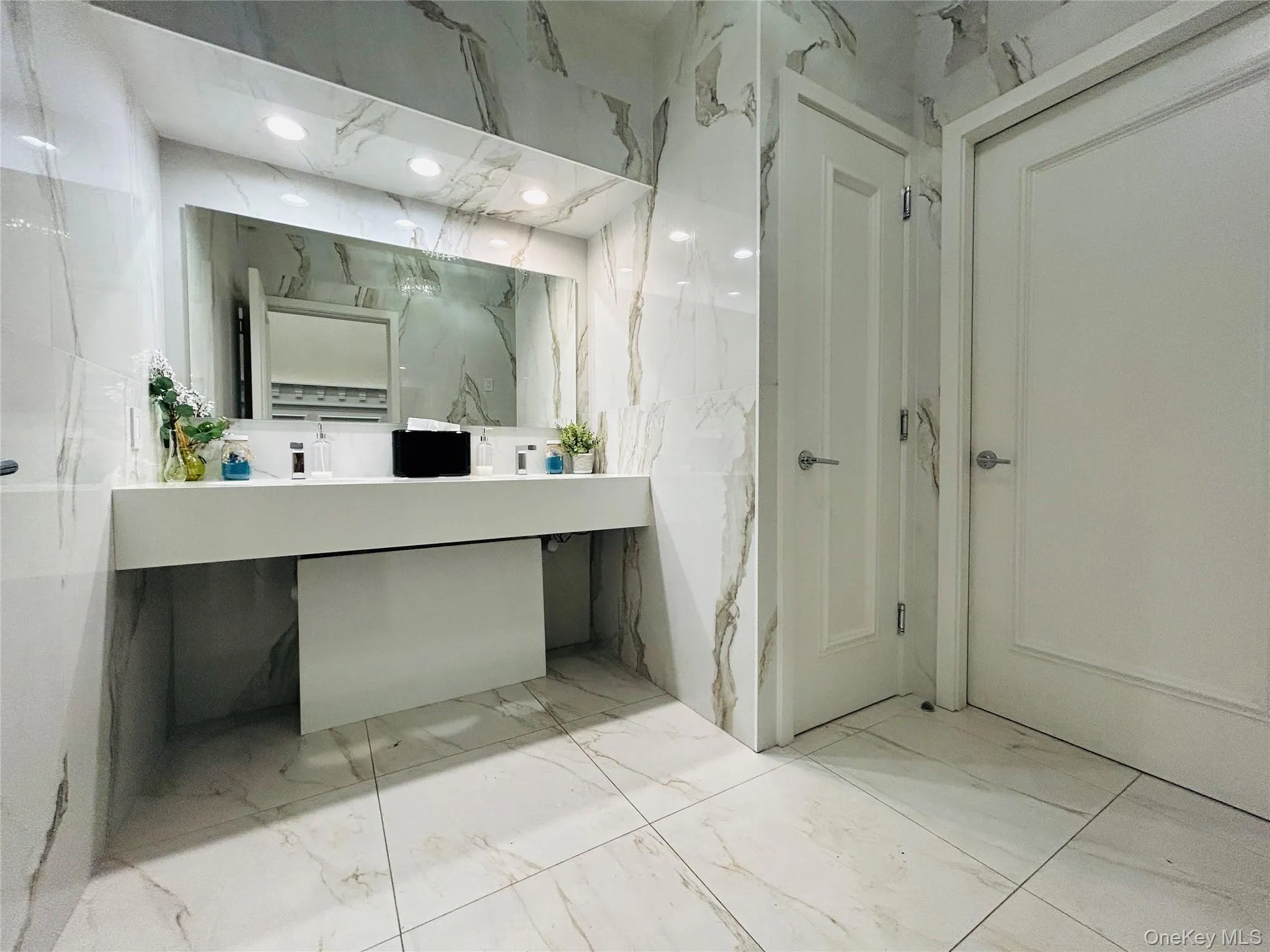 Bathroom with light marble finish flooring, stone wall, vanity, tile walls, and recessed lighting Bathroom with light marble finish flooring, stone wall, vanity, tile walls, and recessed lighting