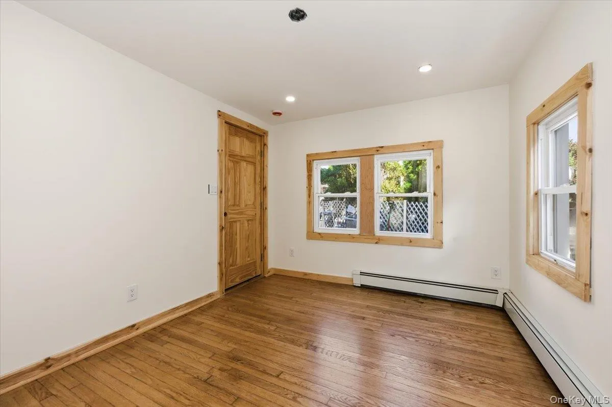 Empty room with a baseboard heating unit, hardwood / wood-style floors, and recessed lighting Empty room with a baseboard heating unit, hardwood / wood-style floors, and recessed lighting