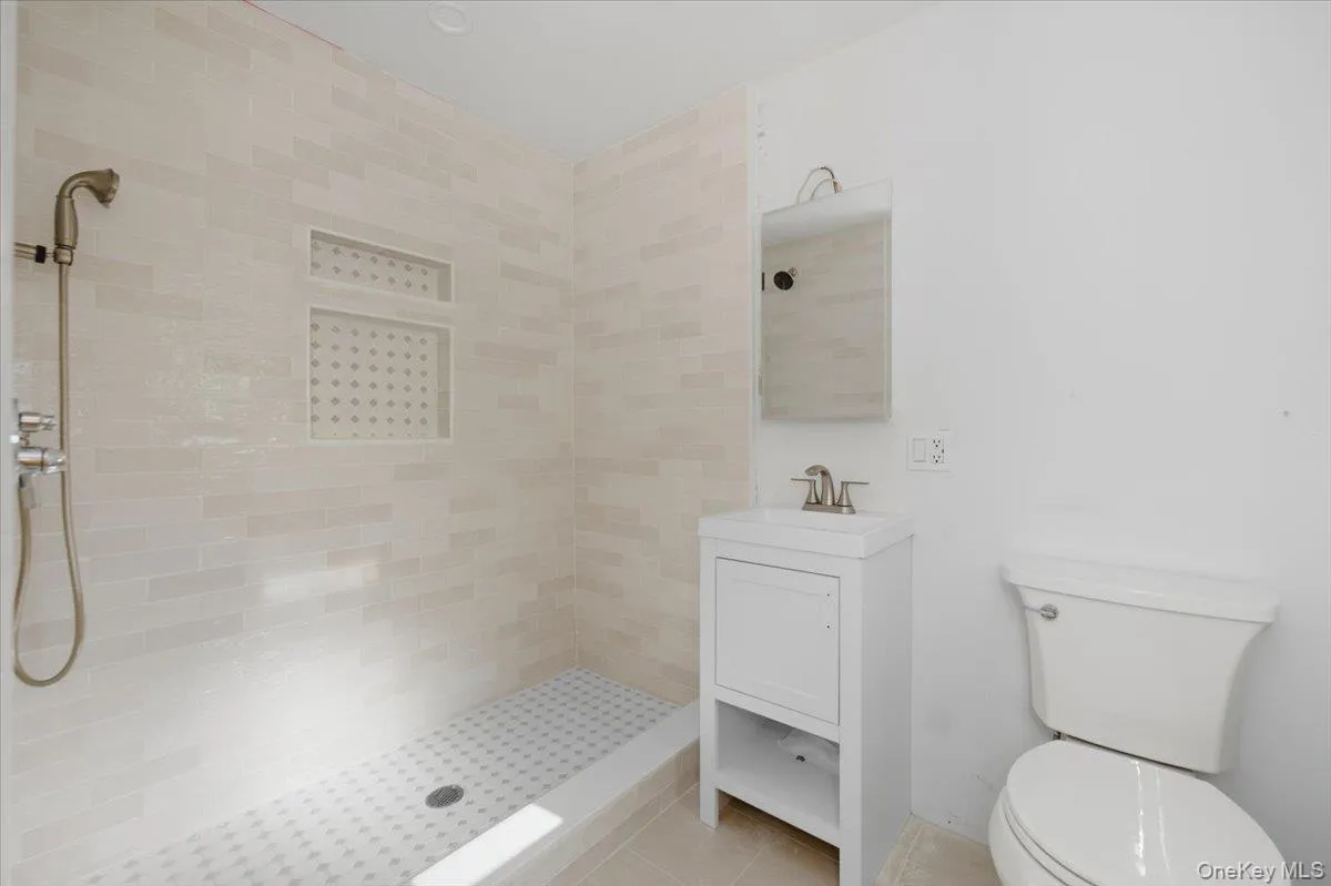 Full bathroom with tiled shower, vanity, and tile patterned flooring Full bathroom with tiled shower, vanity, and tile patterned flooring