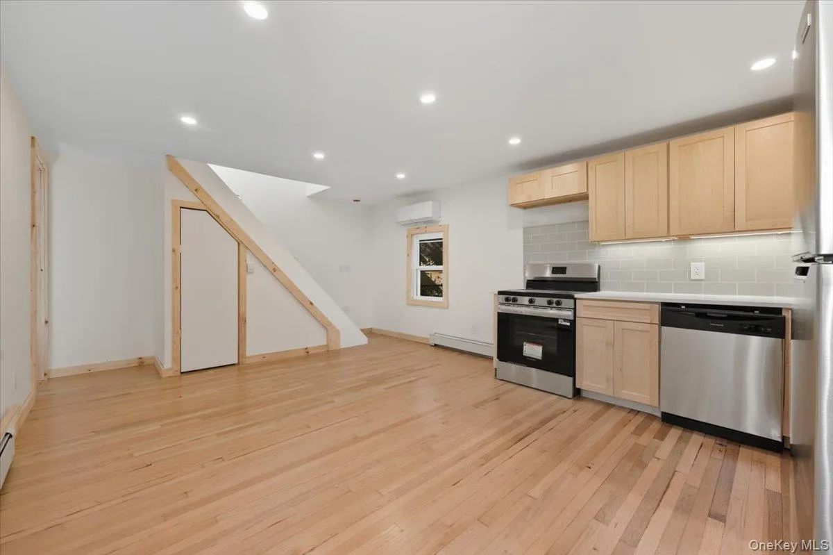 Kitchen with light brown cabinets, light countertops, appliances with stainless steel finishes, tasteful backsplash, and light wood finished floors Kitchen with light brown cabinets, light countertops, appliances with stainless steel finishes, tasteful backsplash, and light wood finished floors