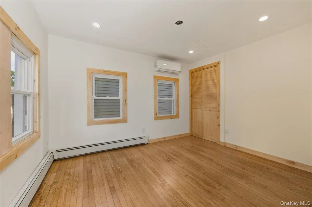 Spare room featuring light wood-style flooring, baseboard heating, recessed lighting, and a wall mounted AC Spare room featuring light wood-style flooring, baseboard heating, recessed lighting, and a wall mounted AC