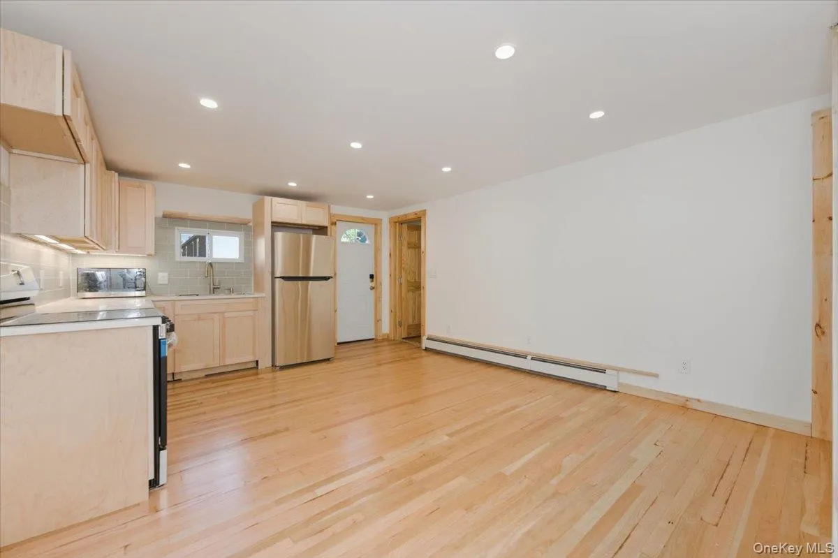 Kitchen featuring light brown cabinets, range with electric cooktop, light countertops, freestanding refrigerator, and tasteful backsplash Kitchen featuring light brown cabinets, range with electric cooktop, light countertops, freestanding refrigerator, and tasteful backsplash