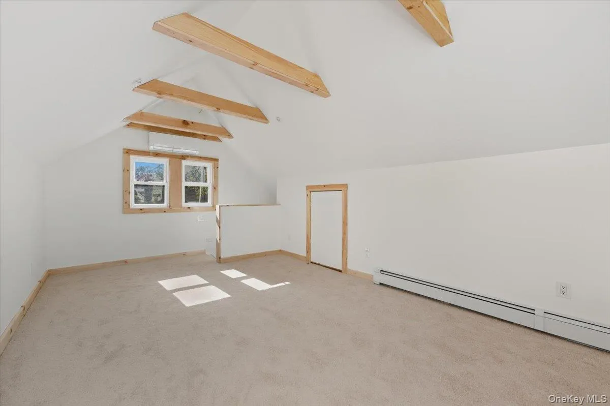 Bonus room featuring light carpet, a baseboard heating unit, and an AC wall unit Bonus room featuring light carpet, a baseboard heating unit, and an AC wall unit