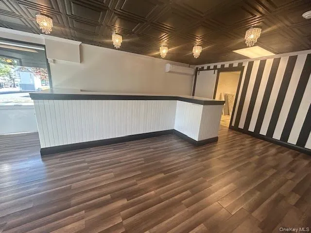 Bar with white cabinets, an ornate ceiling, hanging light fixtures, and a wall unit AC Bar with white cabinets, an ornate ceiling, hanging light fixtures, and a wall unit AC