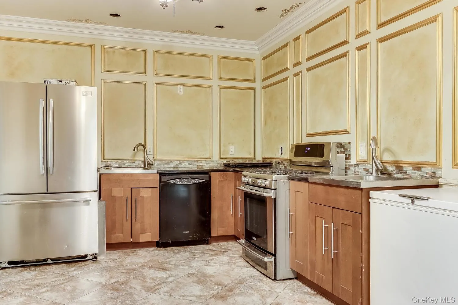 Kitchen with stainless steel appliances, crown molding, light brown cabinetry, and tasteful backsplash Kitchen with stainless steel appliances, crown molding, light brown cabinetry, and tasteful backsplash