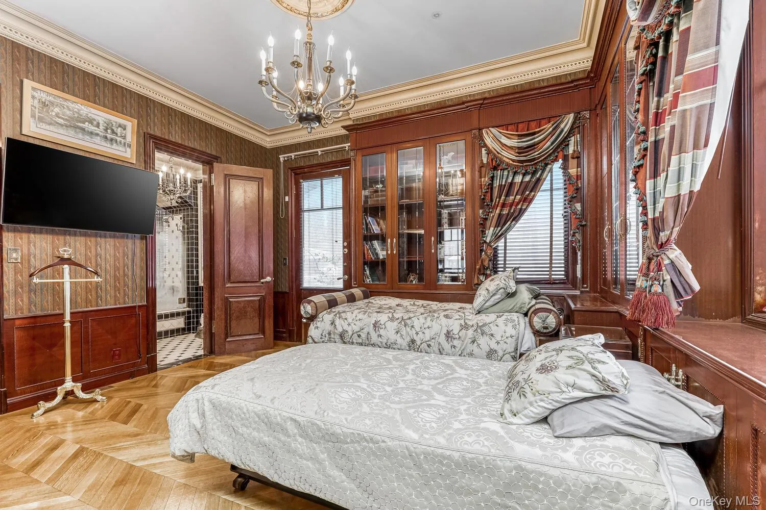 Bedroom with ornamental molding, a chandelier, and wallpapered walls Bedroom with ornamental molding, a chandelier, and wallpapered walls