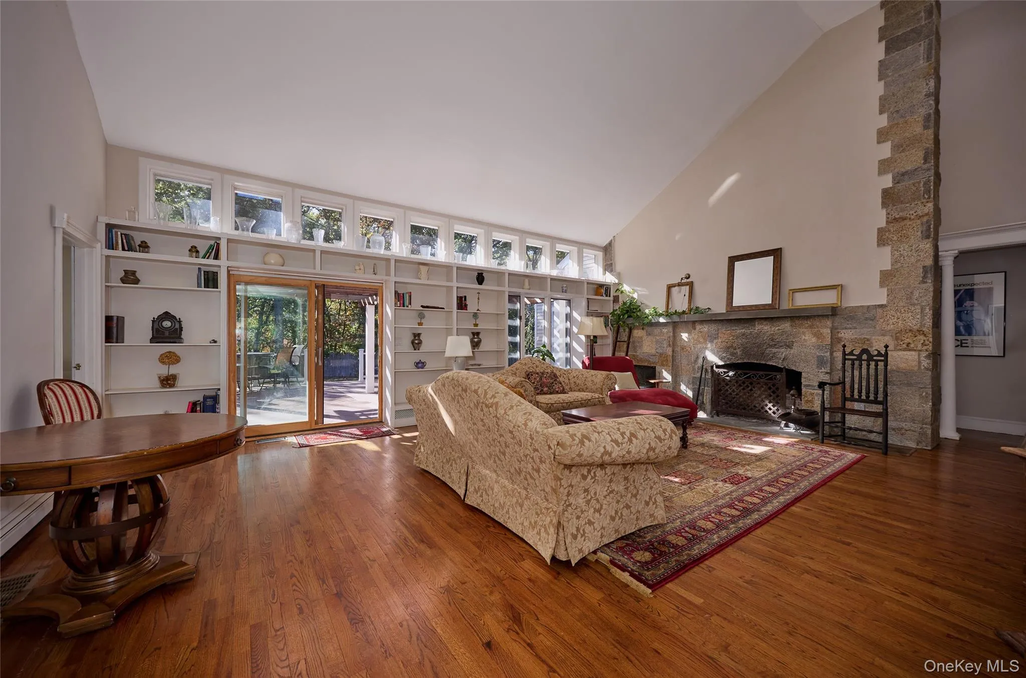 Living area featuring high vaulted ceiling, plenty of natural light, a fireplace, and wood finished floors Living area featuring high vaulted ceiling, plenty of natural light, a fireplace, and wood finished floors