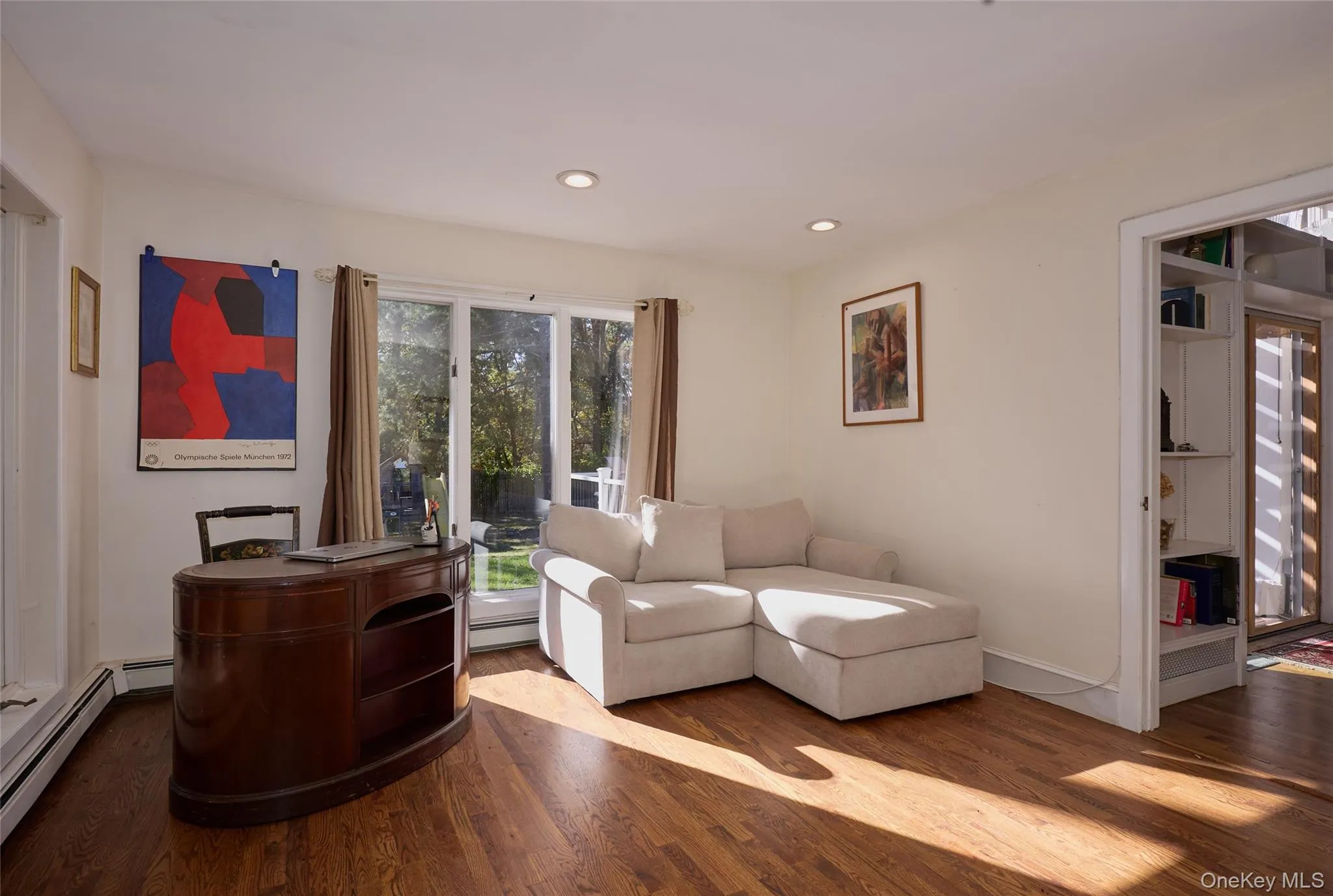 Living area featuring wood finished floors, recessed lighting, and baseboard heating Living area featuring wood finished floors, recessed lighting, and baseboard heating