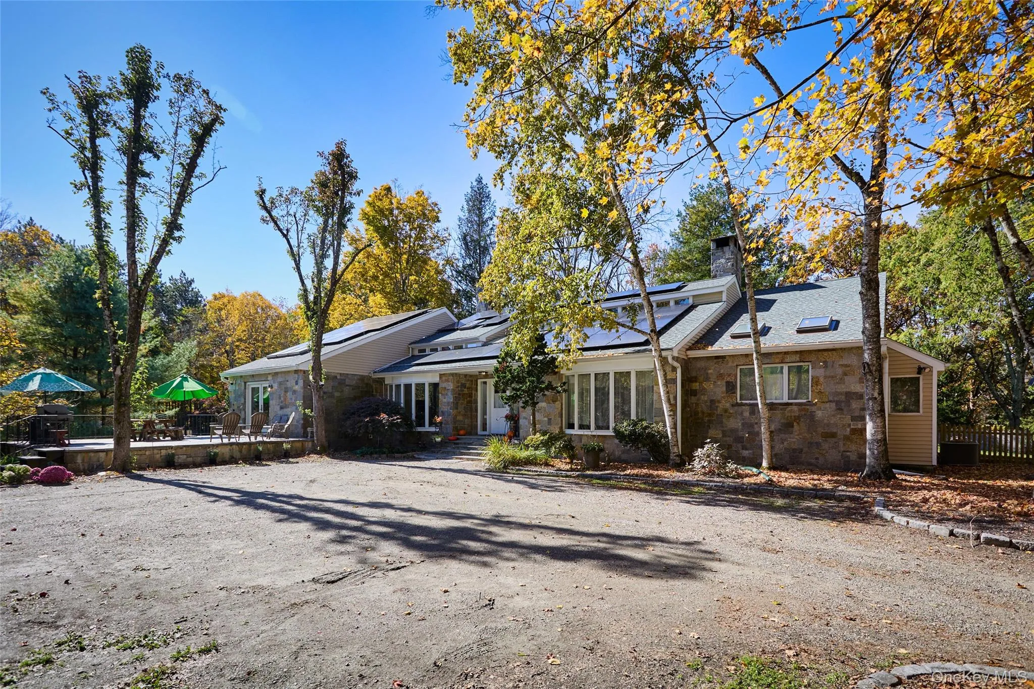 Mid-century home with stone siding, solar panels, and a chimney Mid-century home with stone siding, solar panels, and a chimney