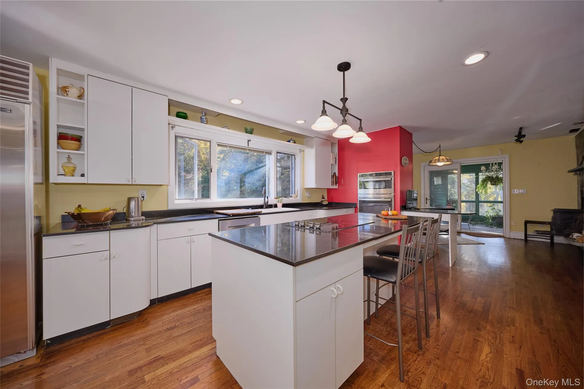 Kitchen with white cabinetry, recessed lighting, hanging light fixtures, a breakfast bar area, and light wood-style floors Kitchen with white cabinetry, recessed lighting, hanging light fixtures, a breakfast bar area, and light wood-style floors