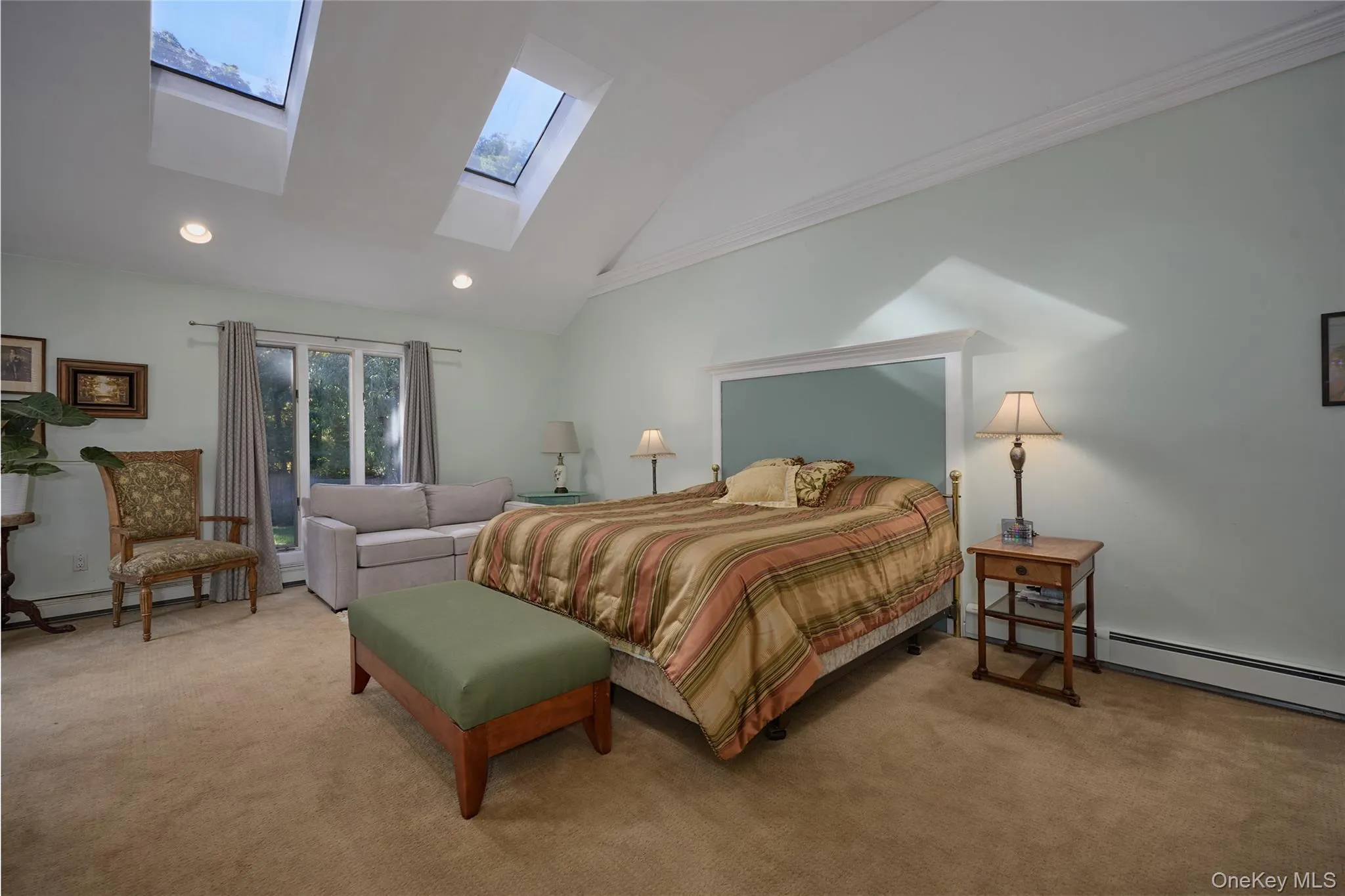 Carpeted bedroom with high vaulted ceiling, recessed lighting, a baseboard heating unit, and a skylight Carpeted bedroom with high vaulted ceiling, recessed lighting, a baseboard heating unit, and a skylight