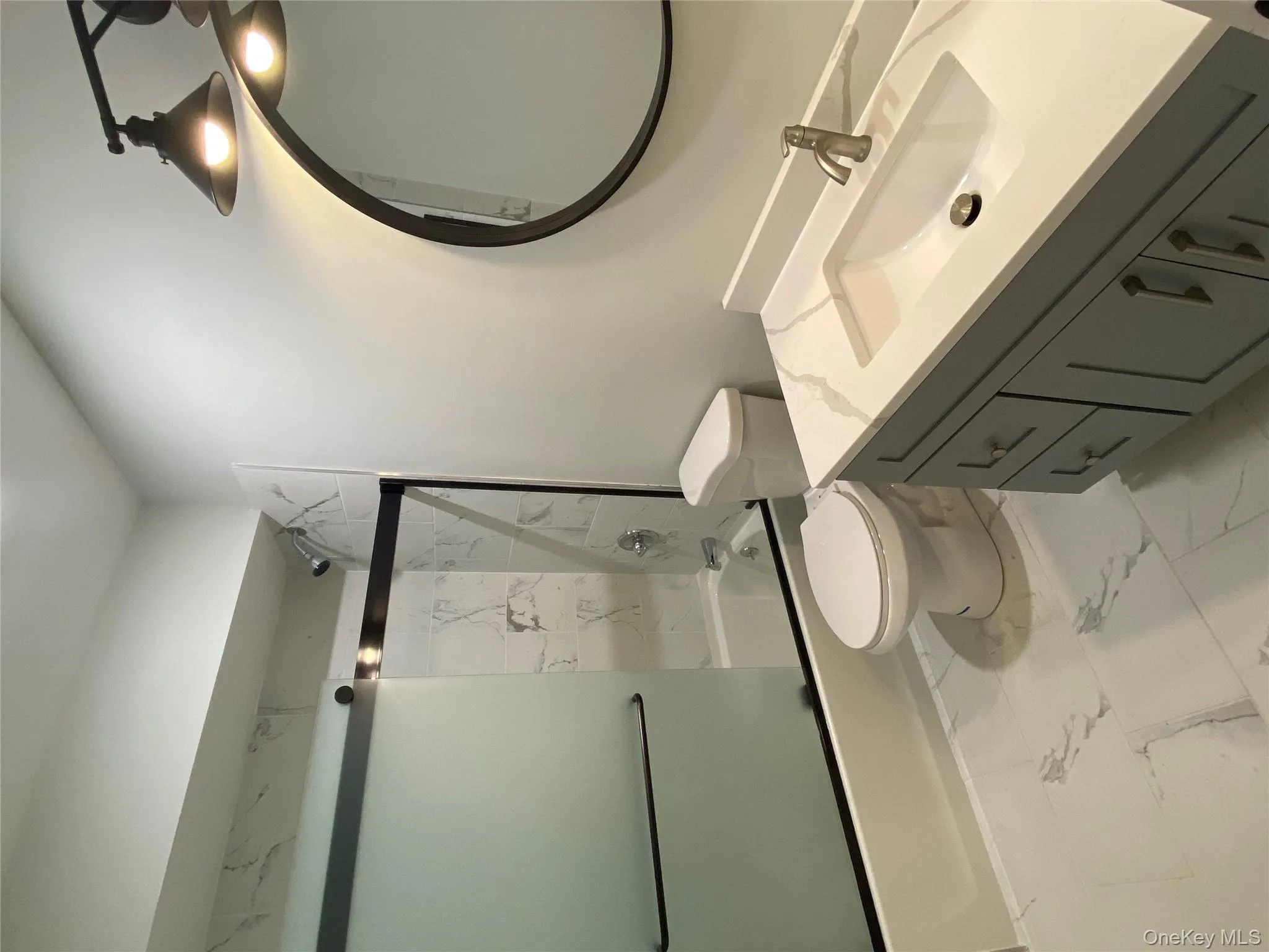 Hall Bathroom with vanity, combined bath / shower with glass door, and light marble finish flooring Hall Bathroom with vanity, combined bath / shower with glass door, and light marble finish flooring