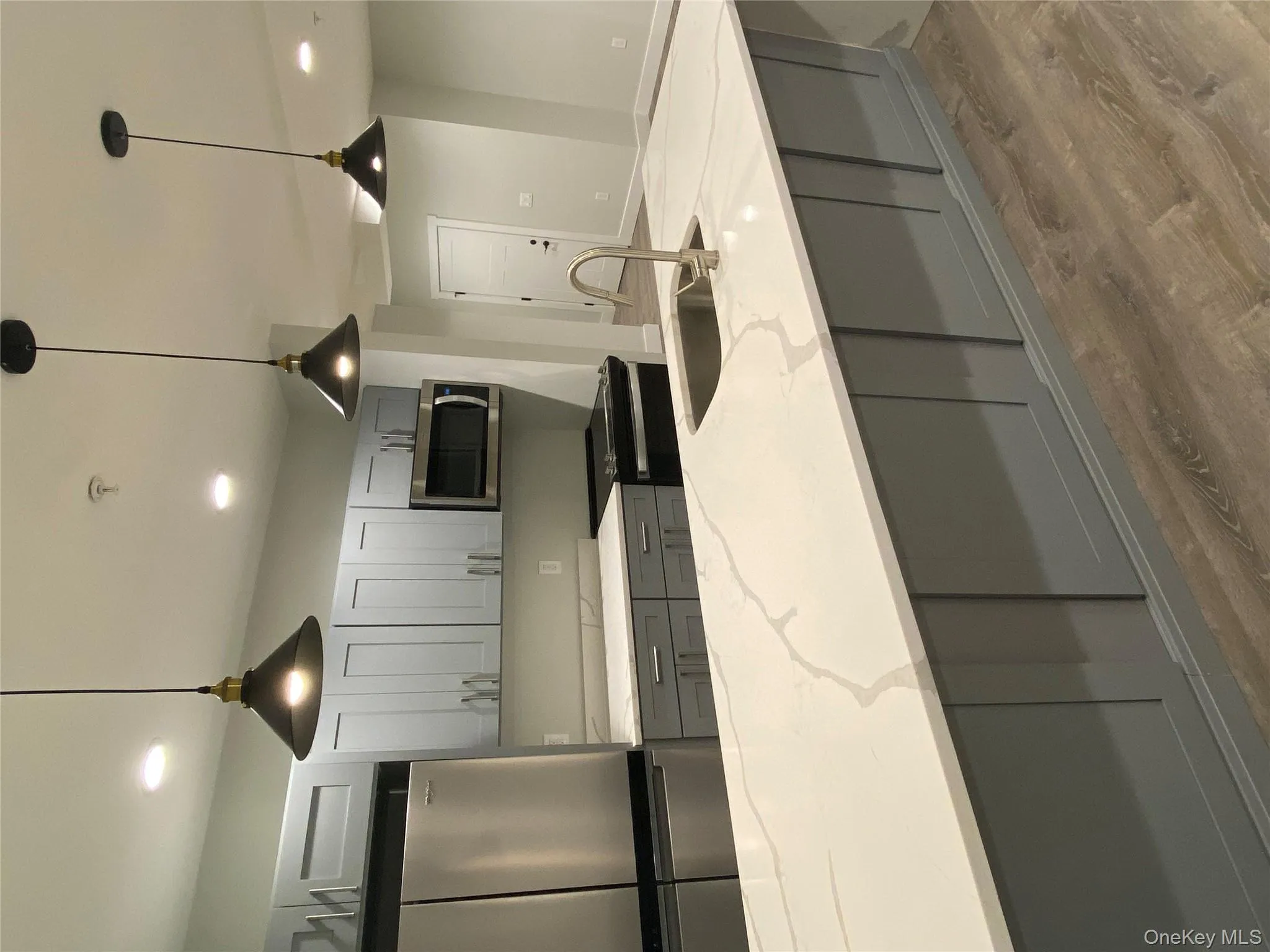 Kitchen featuring decorative light fixtures, fridge, gray cabinets, wood finished floors, and recessed lighting Kitchen featuring decorative light fixtures, fridge, gray cabinets, wood finished floors, and recessed lighting