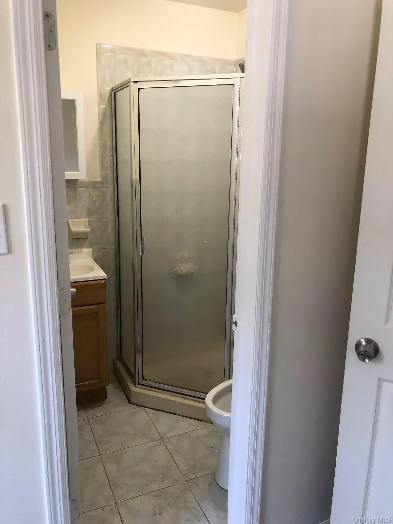 Bathroom with vanity, a stall shower, tile walls, and light tile patterned flooring Bathroom with vanity, a stall shower, tile walls, and light tile patterned flooring