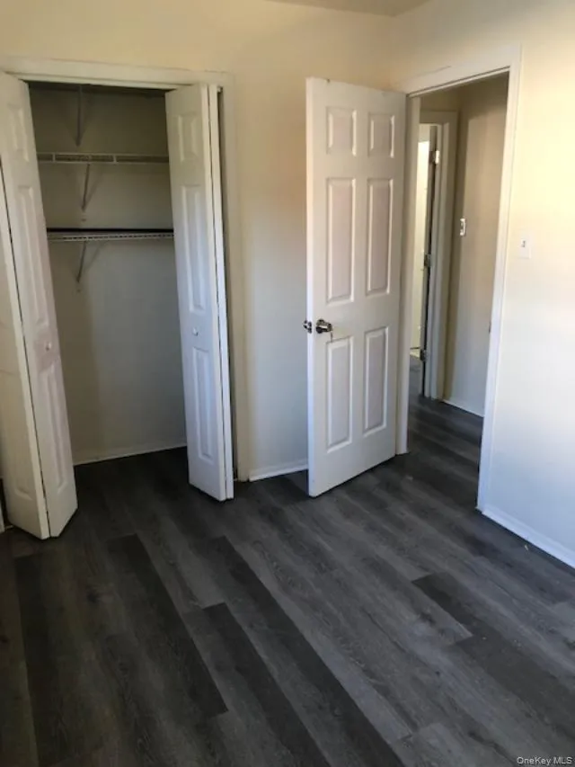 Unfurnished bedroom featuring dark wood-style floors and a closet Unfurnished bedroom featuring dark wood-style floors and a closet