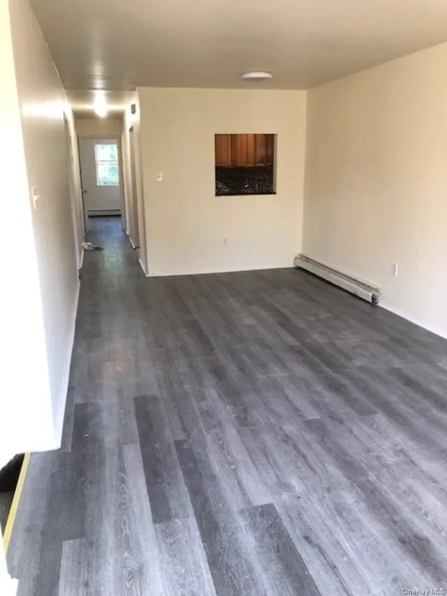 Unfurnished room with a baseboard radiator, dark wood finished floors, and baseboard heating Unfurnished room with a baseboard radiator, dark wood finished floors, and baseboard heating
