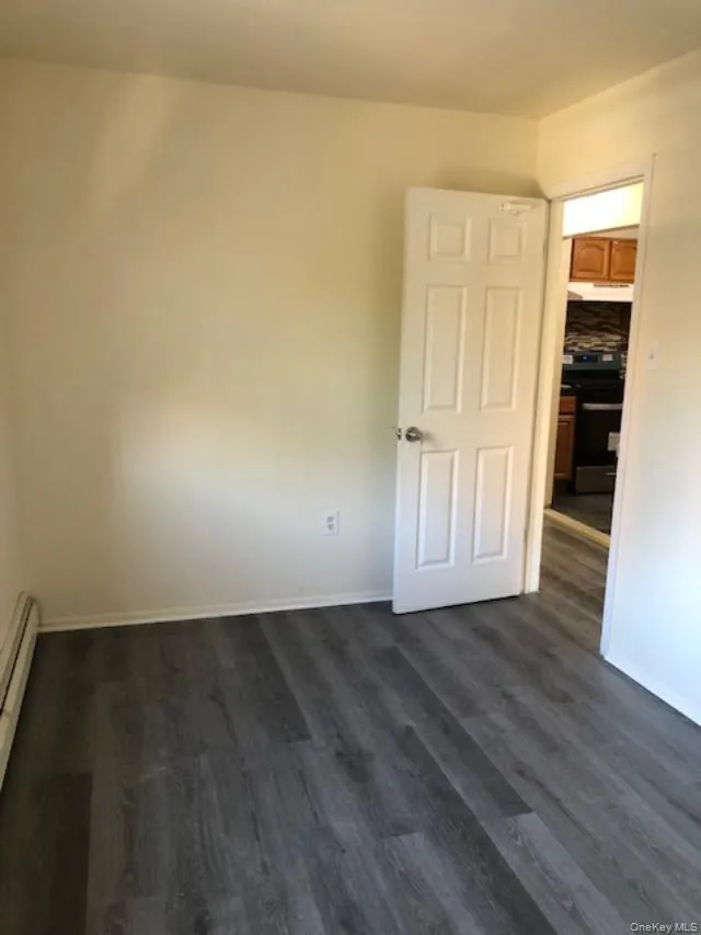 Spare room featuring dark wood finished floors and baseboard heating Spare room featuring dark wood finished floors and baseboard heating